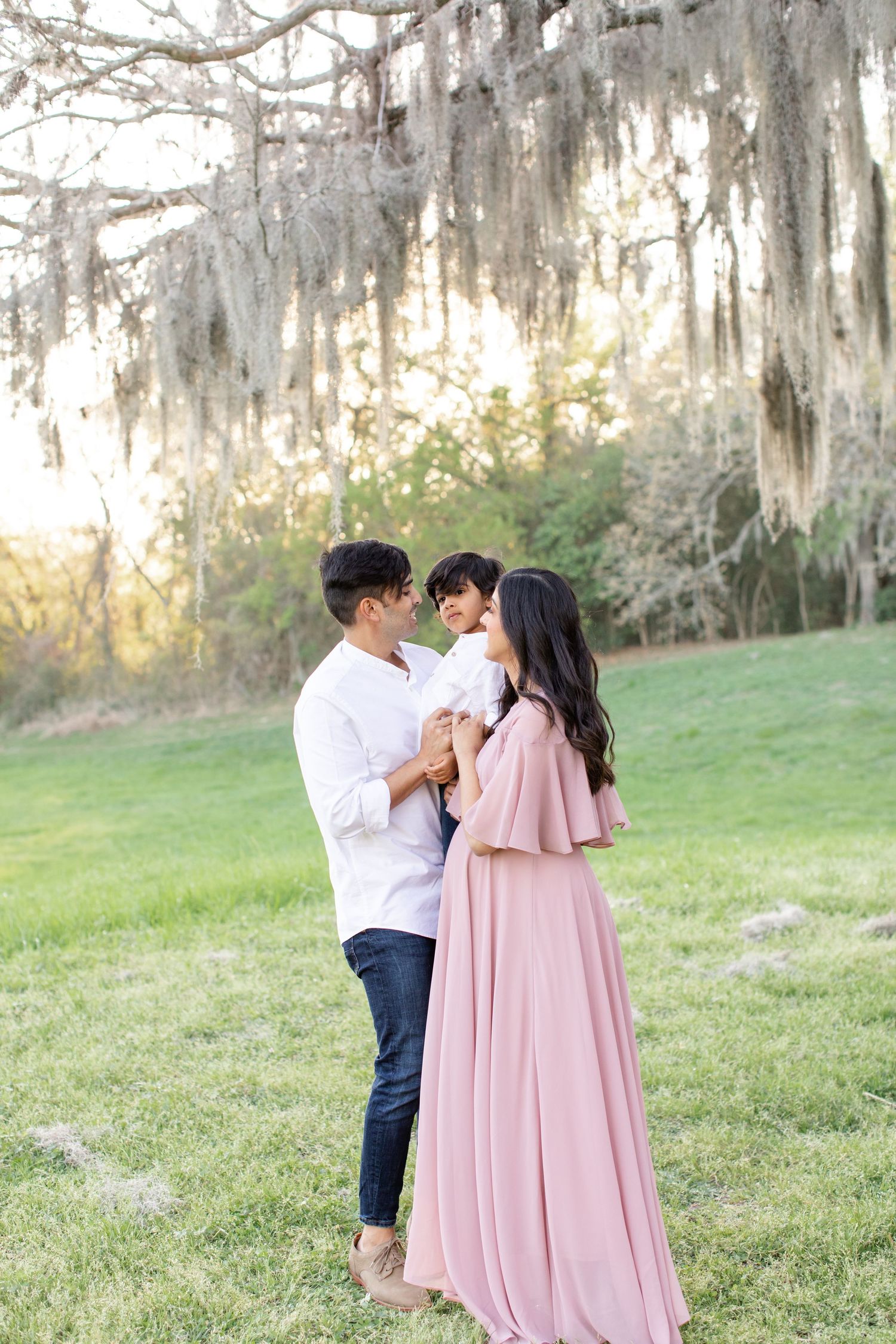 Intimate maternity portrait session in natural outdoor setting with dramatic Spanish moss backdrop.