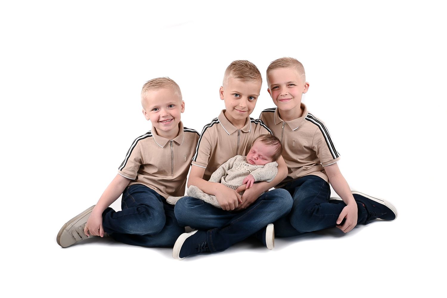 Casual family portrait of siblings in matching outfits on white background.