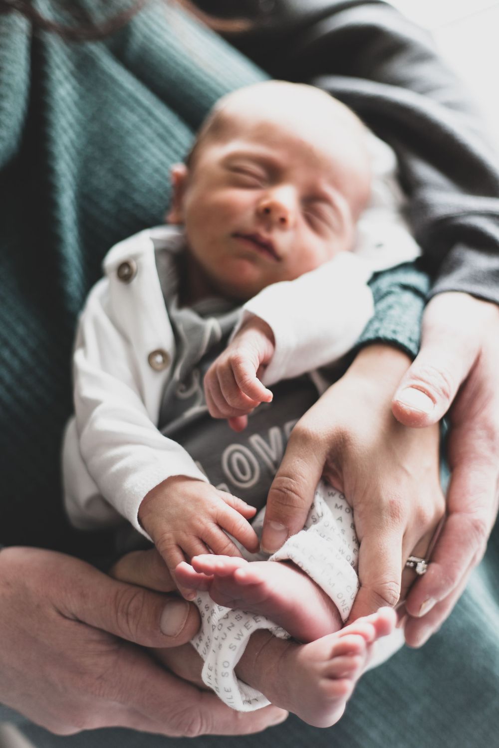 a newborn in his mothers arms with his fathers arms wrapped around him