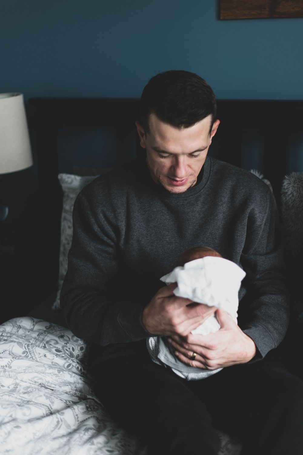 a new father holding his son swaddled up