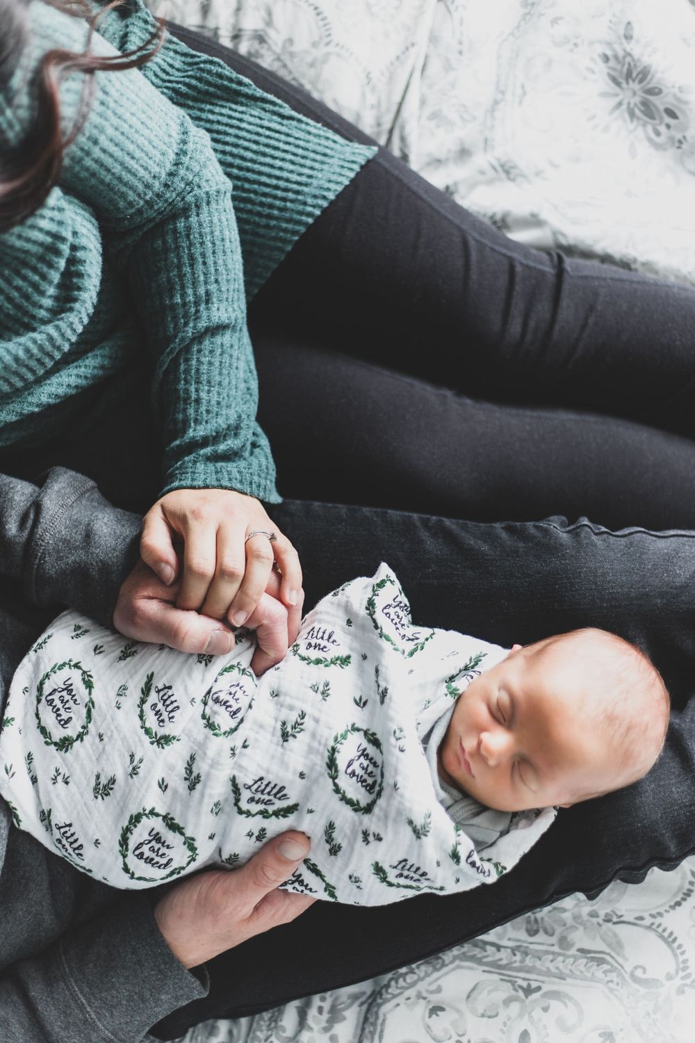 a birds eye view shot of a father and mother sitting next to each other with their newborn in the fathers lap asleep