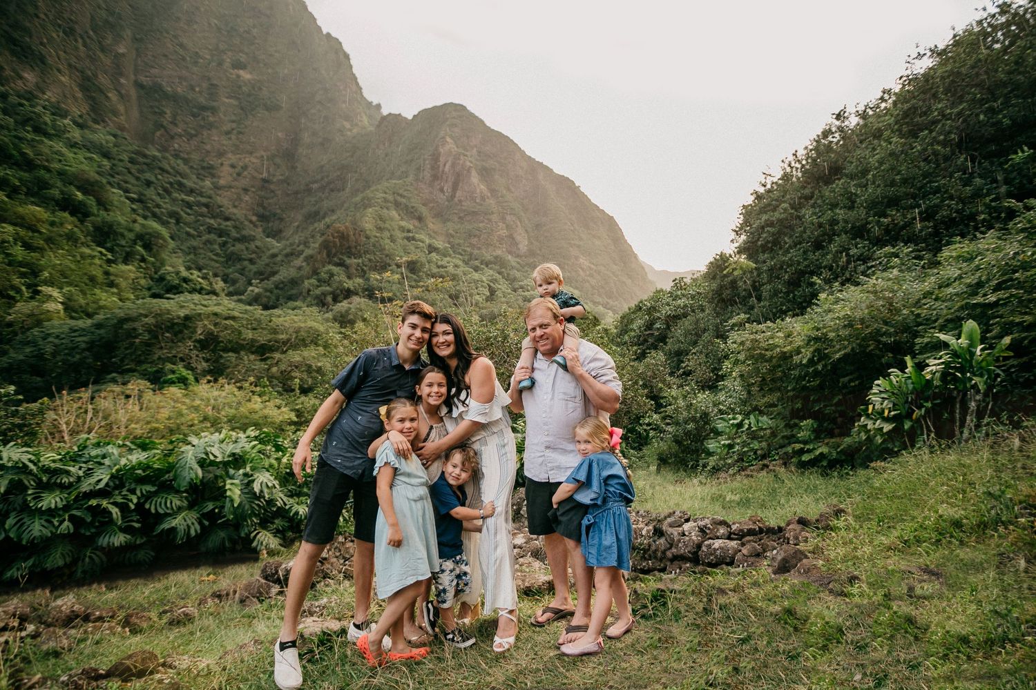 Group poses together in lush valley with dramatic mountain peaks in background.