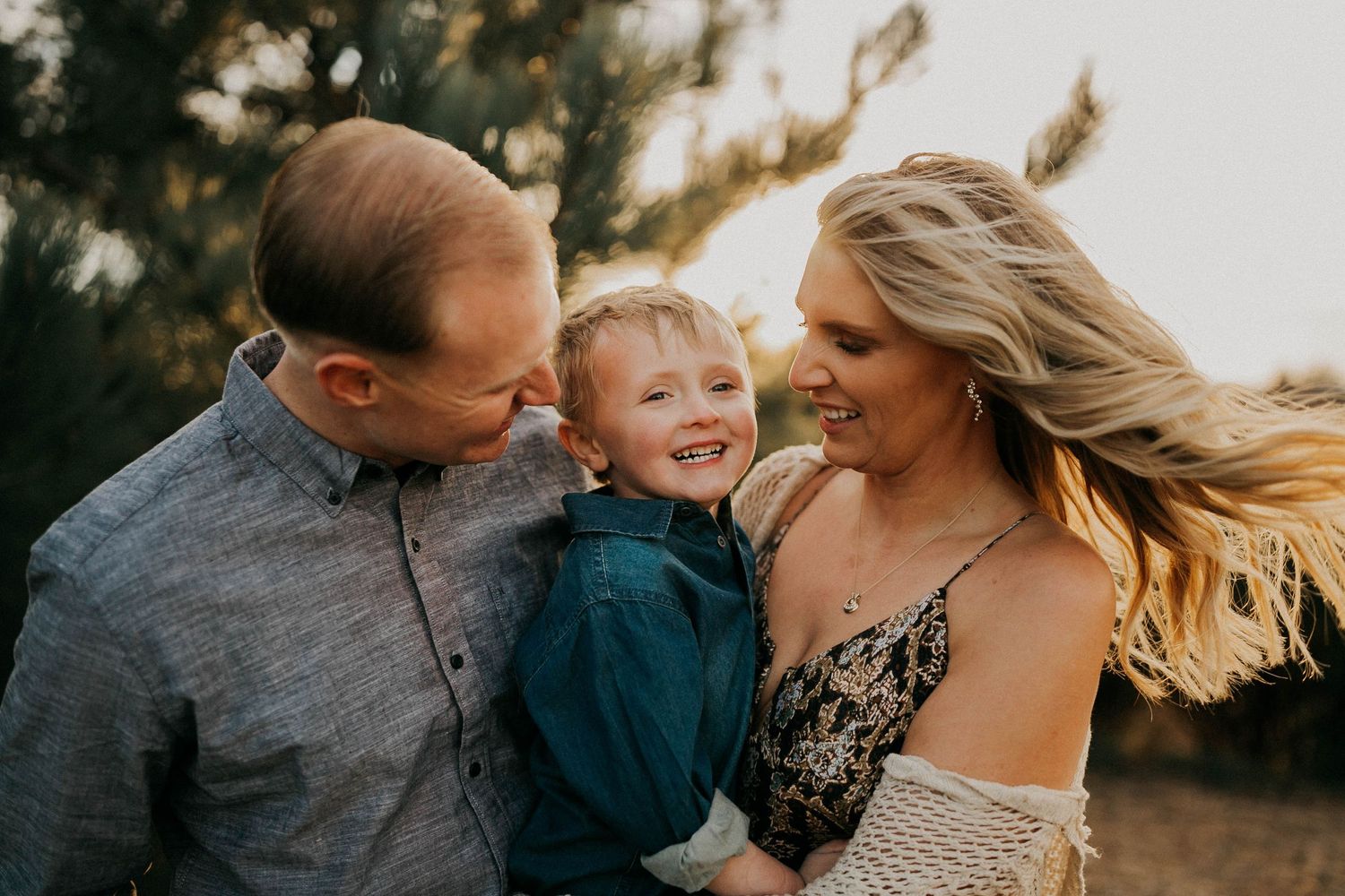 A candid outdoor family moment captured during golden hour with trees in background.
