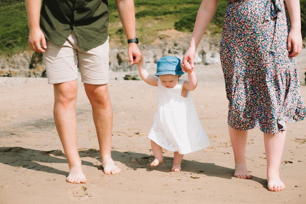 Bare feet walking together on sandy beach near the ocean.