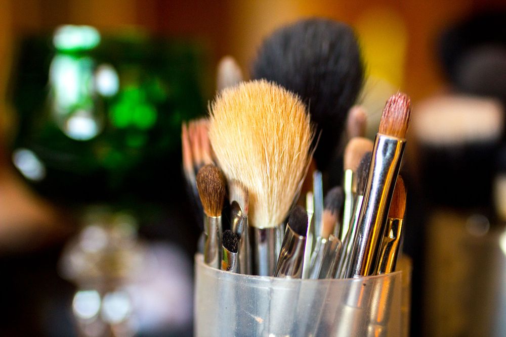 Professional makeup brushes arranged in holders against a warm-toned background.