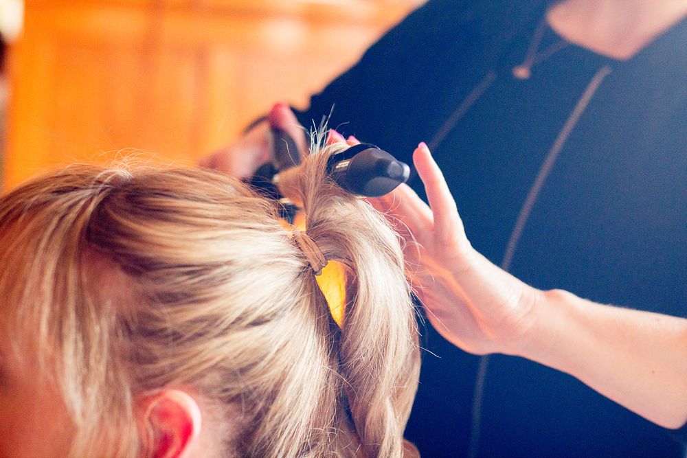Hair styling session captured in warm lighting with professional equipment.