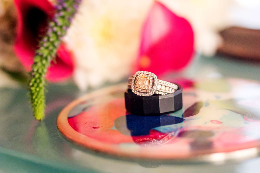 Diamond engagement ring on colorful surface with soft floral elements.