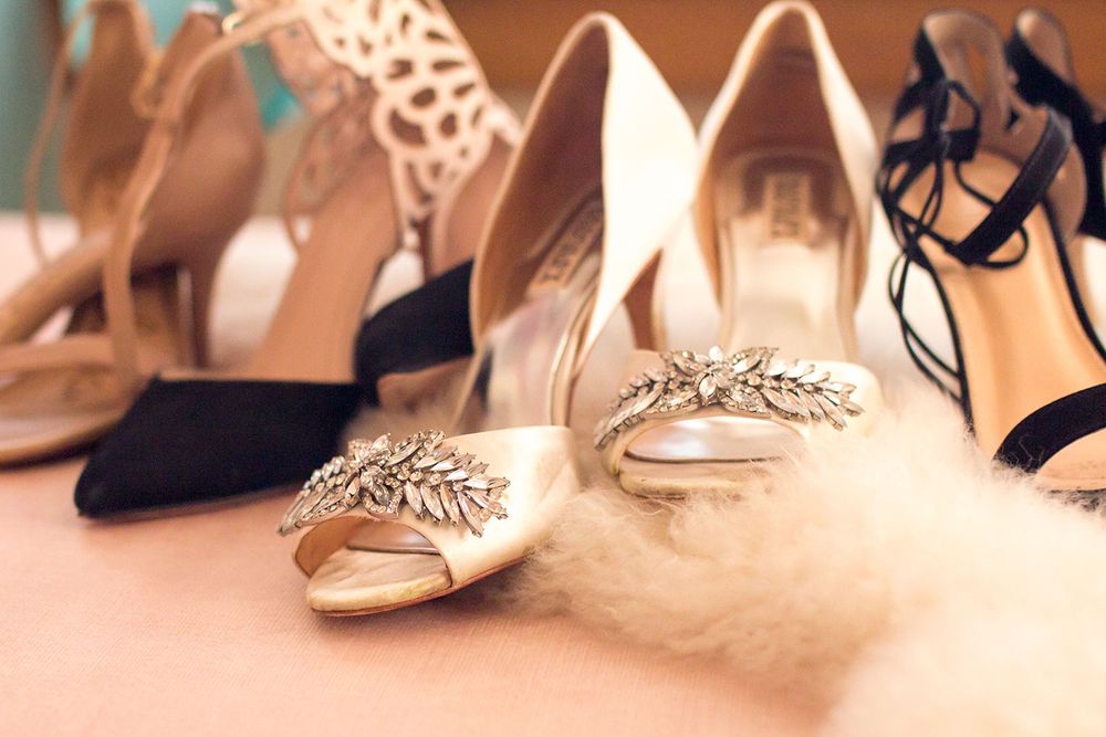 Wedding shoes and accessories arranged on a light colored surface.