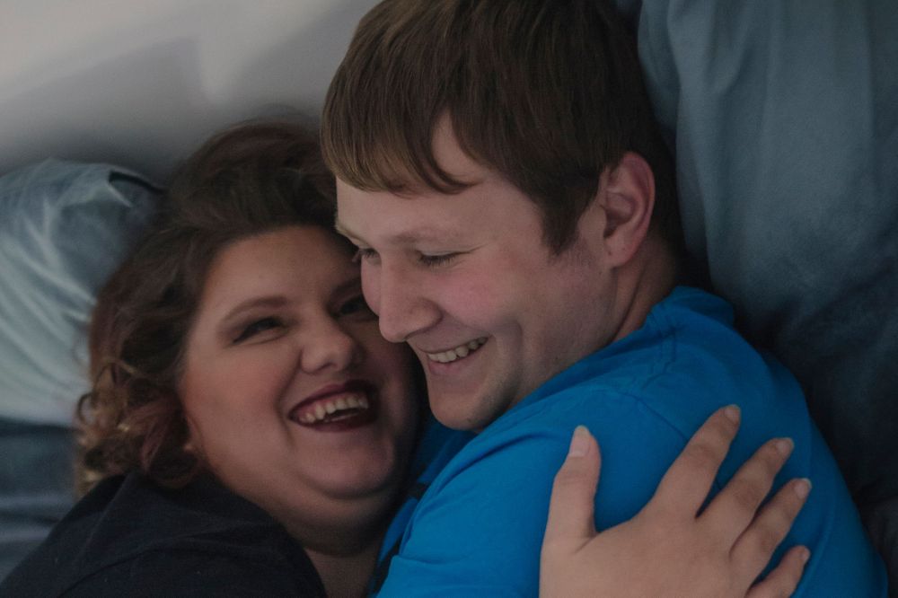 An intimate couple sharing a joyful moment while embracing on a bed.
