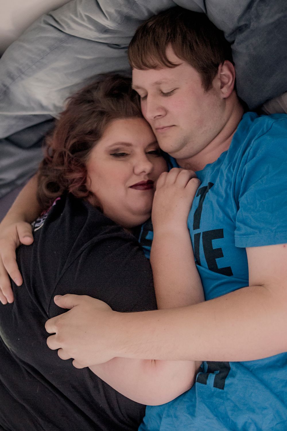 A couple sharing a peaceful moment while cuddling together on blue bedding.