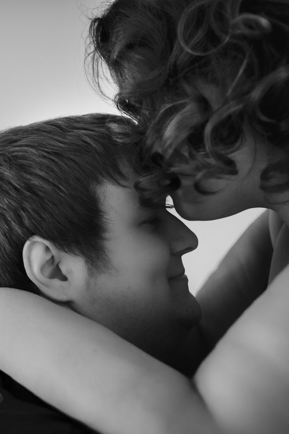 A tender black and white close-up of two people in an intimate embrace.