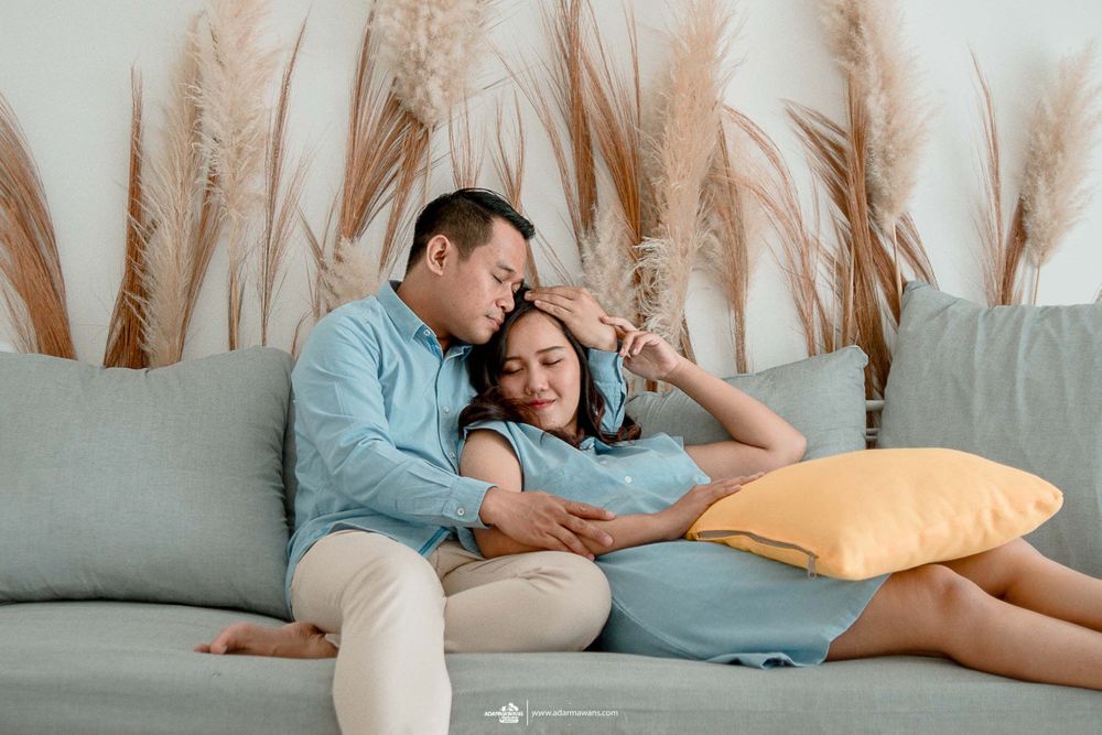 A cozy moment shared on a gray sofa with decorative pampas grass behind.