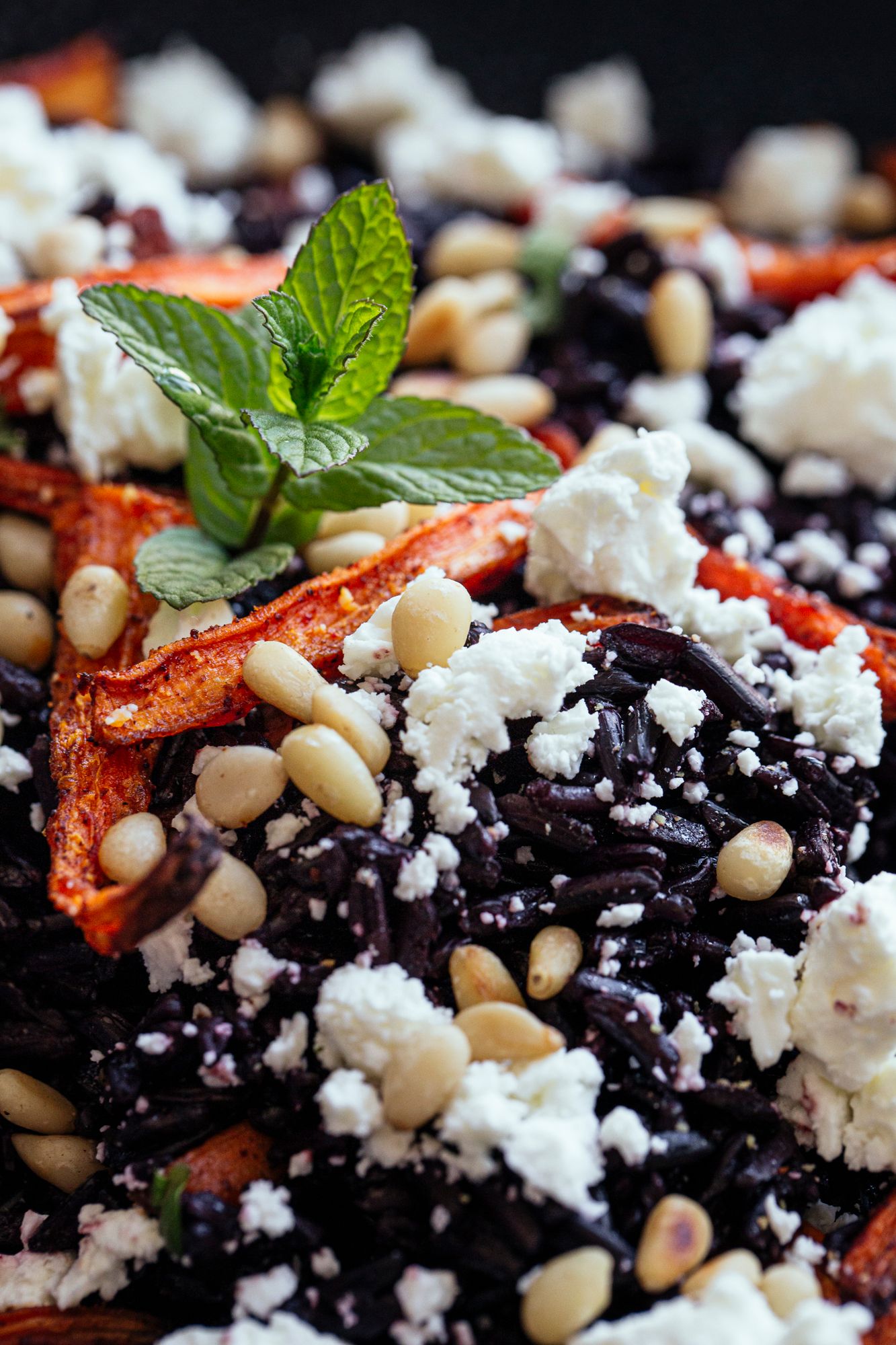 Fresh black rice salad with feta, roasted peppers, pine nuts and mint garnish.