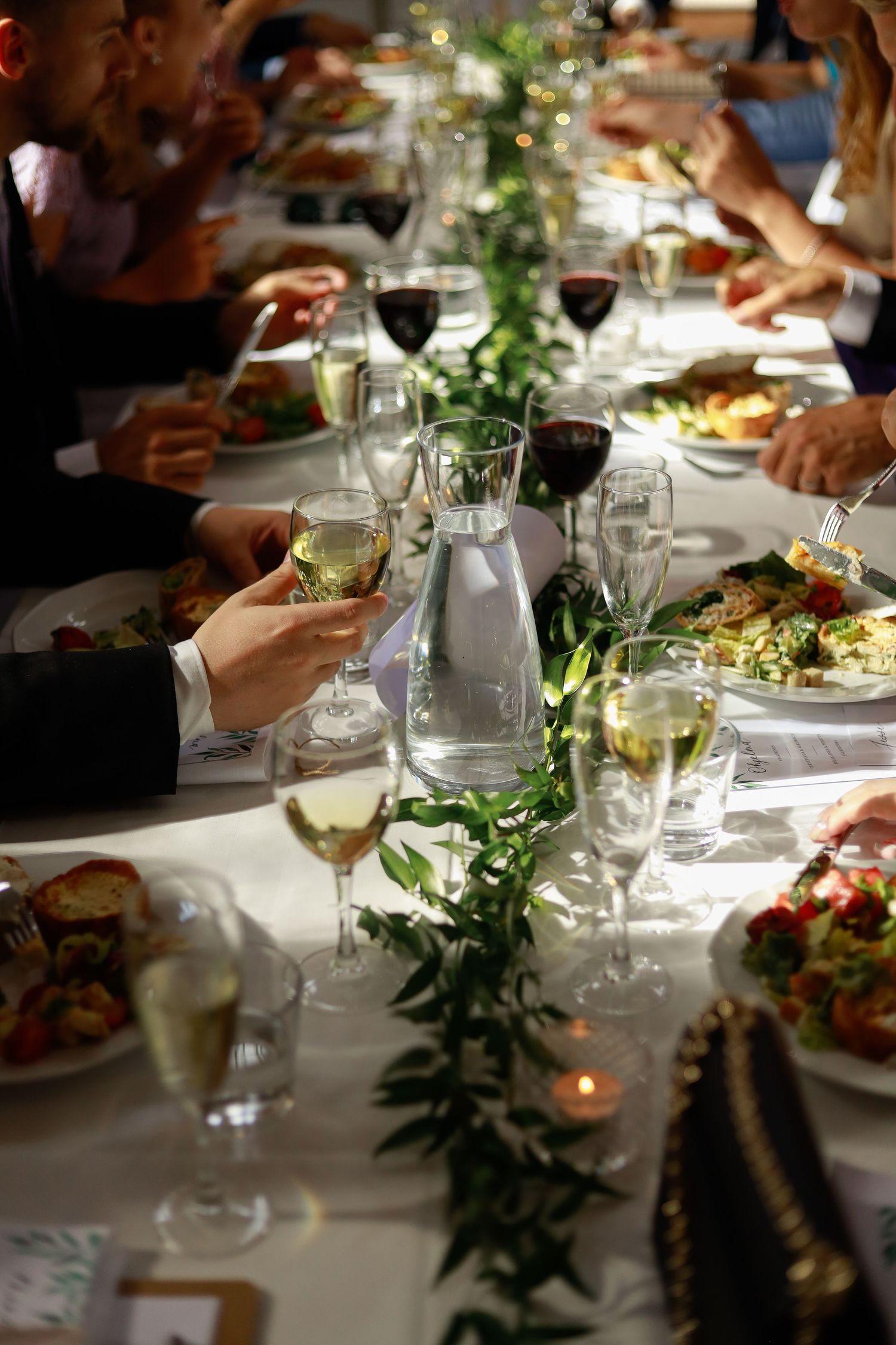 Elegant wedding reception table with wine glasses and greenery garland.