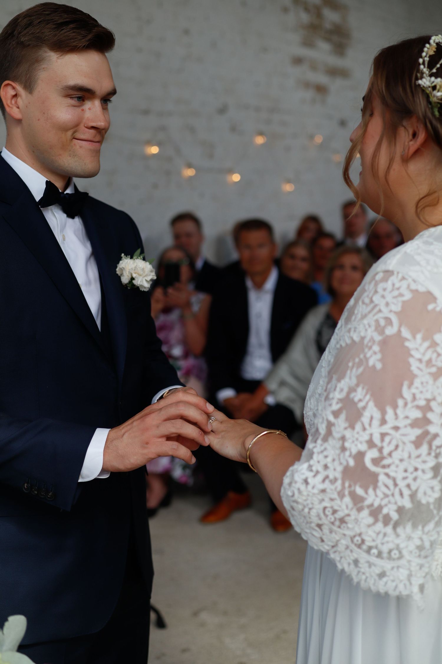 A tender moment during a wedding ceremony in an industrial-style venue with white brick walls.