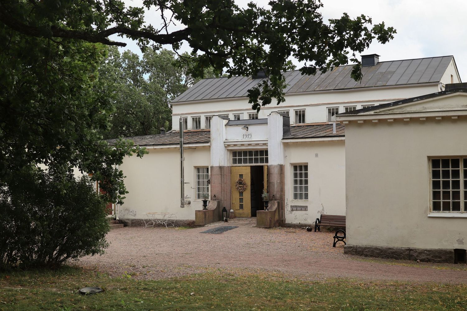 White historic building entrance with gravel path and gardens.