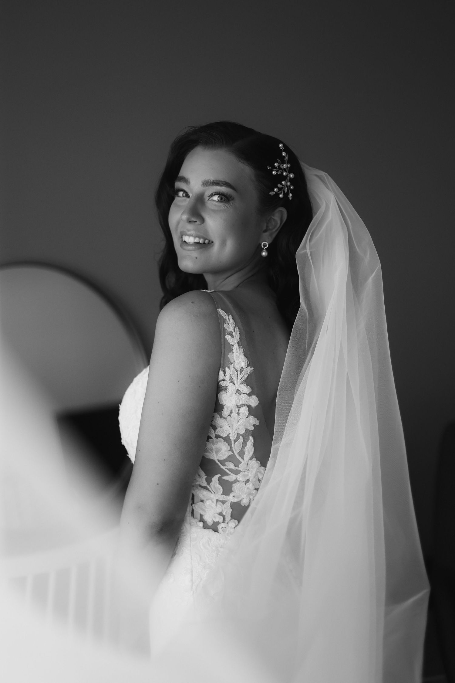 Elegant bridal portrait in black and white featuring lace detail and flowing veil.