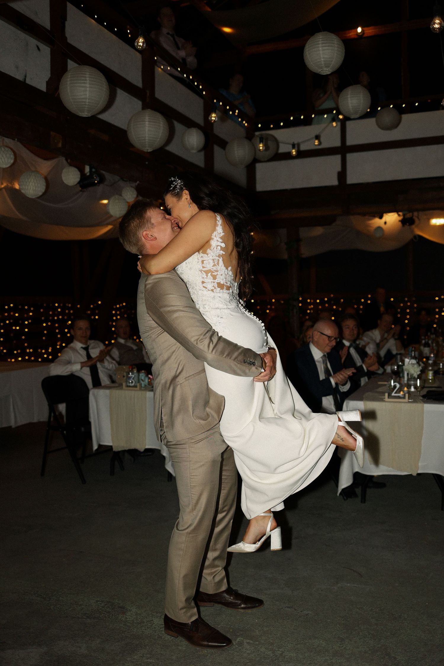 A celebratory reception moment with newlyweds dancing under paper lanterns.