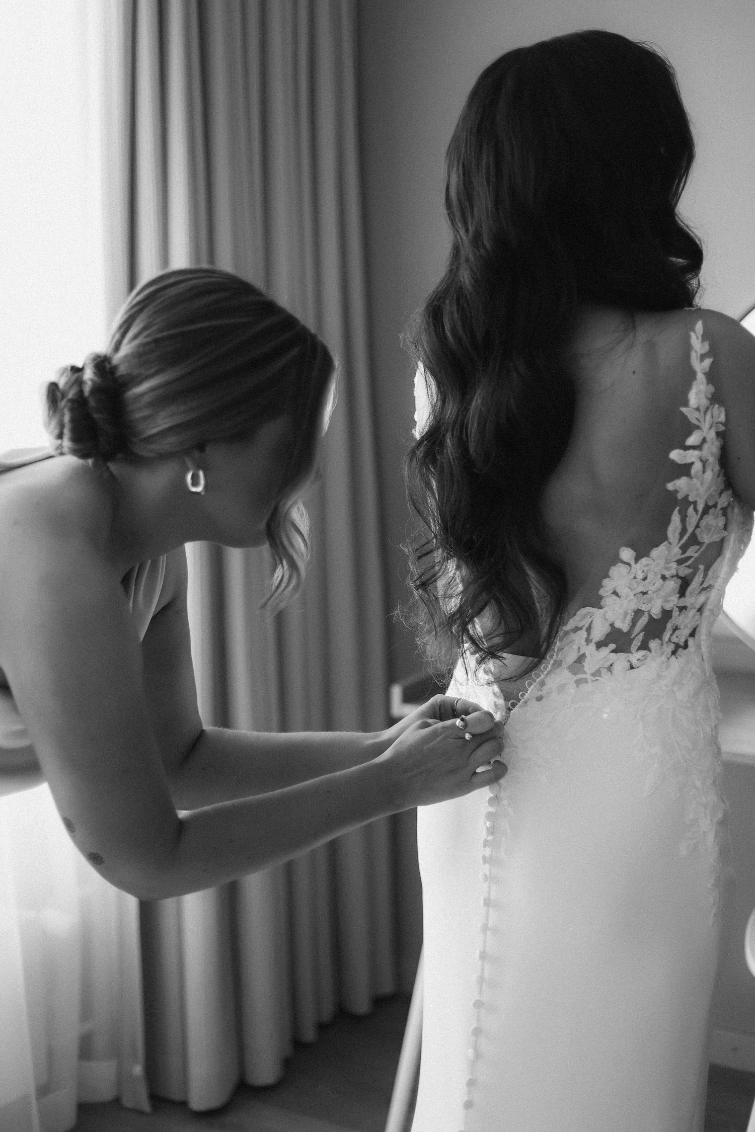 Behind-the-scenes moment of wedding dress preparation in black and white.