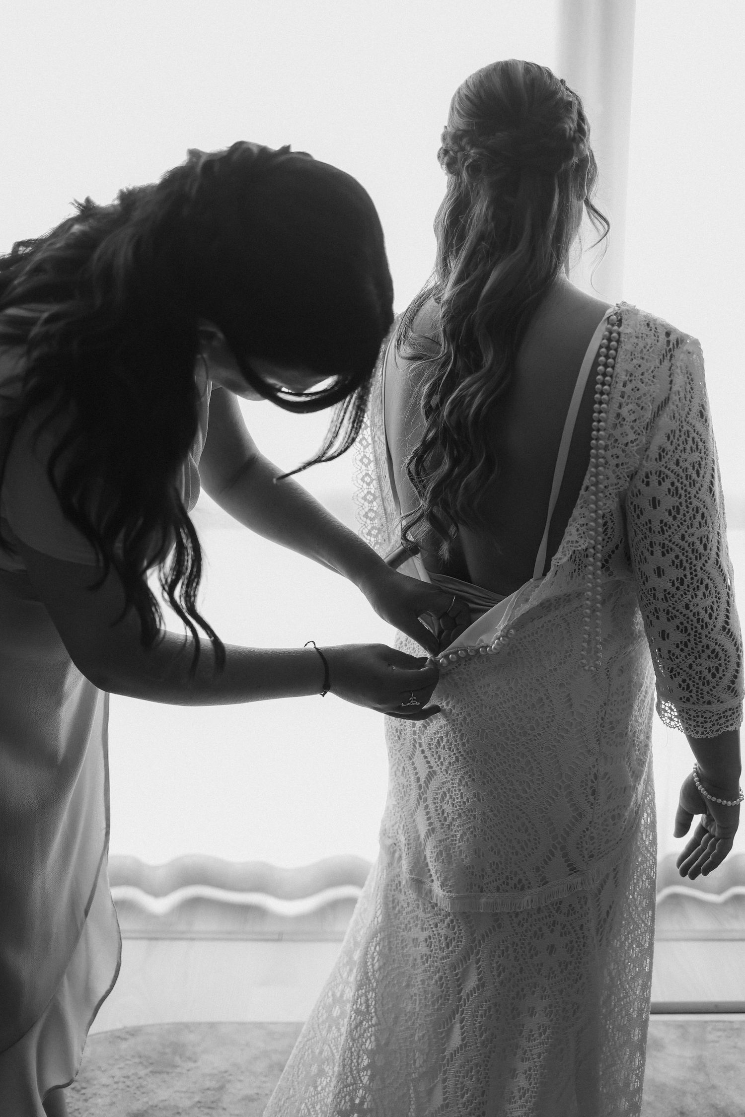 Black and white photo of wedding dress preparation with intricate lace details.