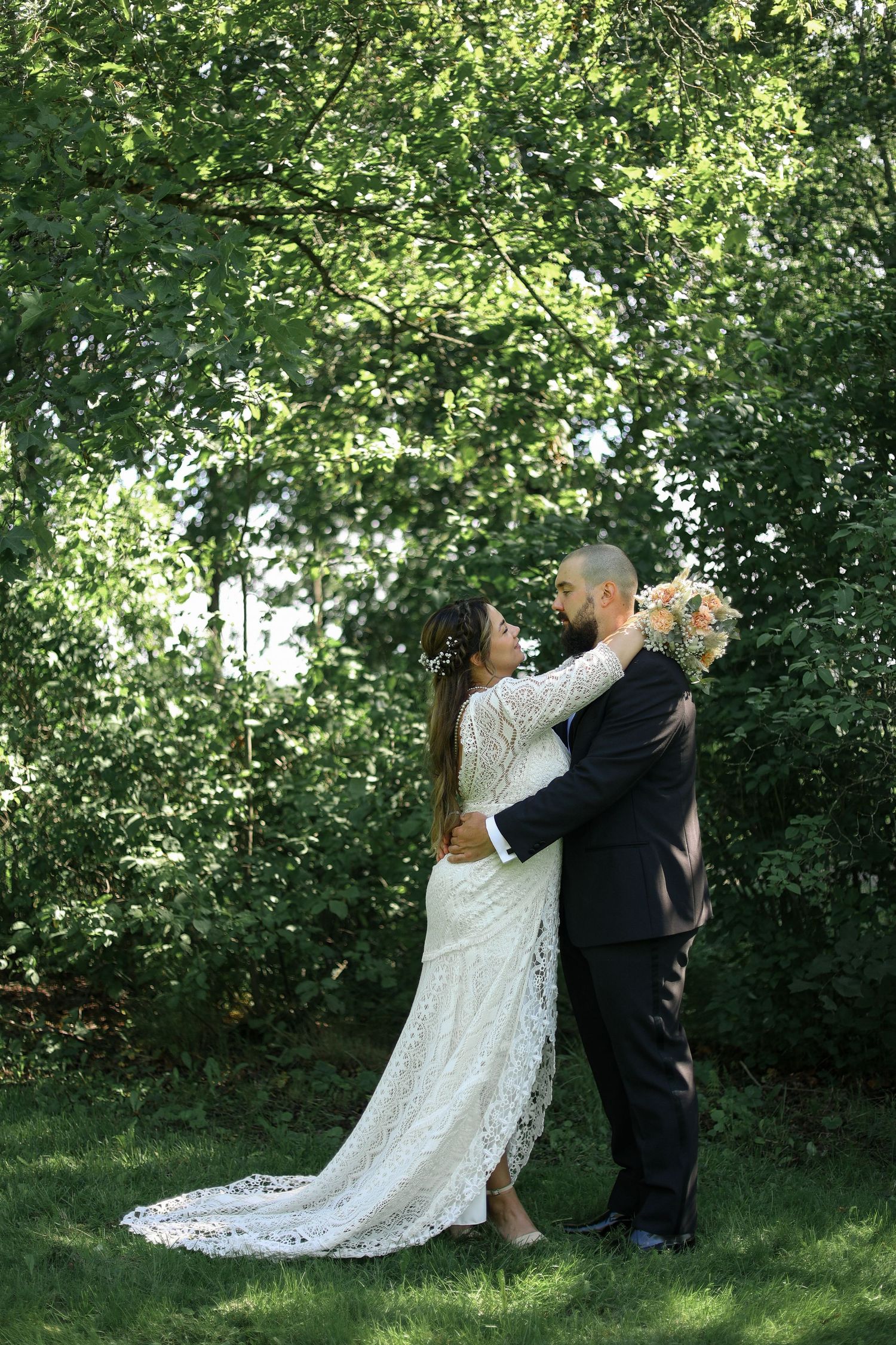 Bride and groom share intimate dance moment in lush garden setting.