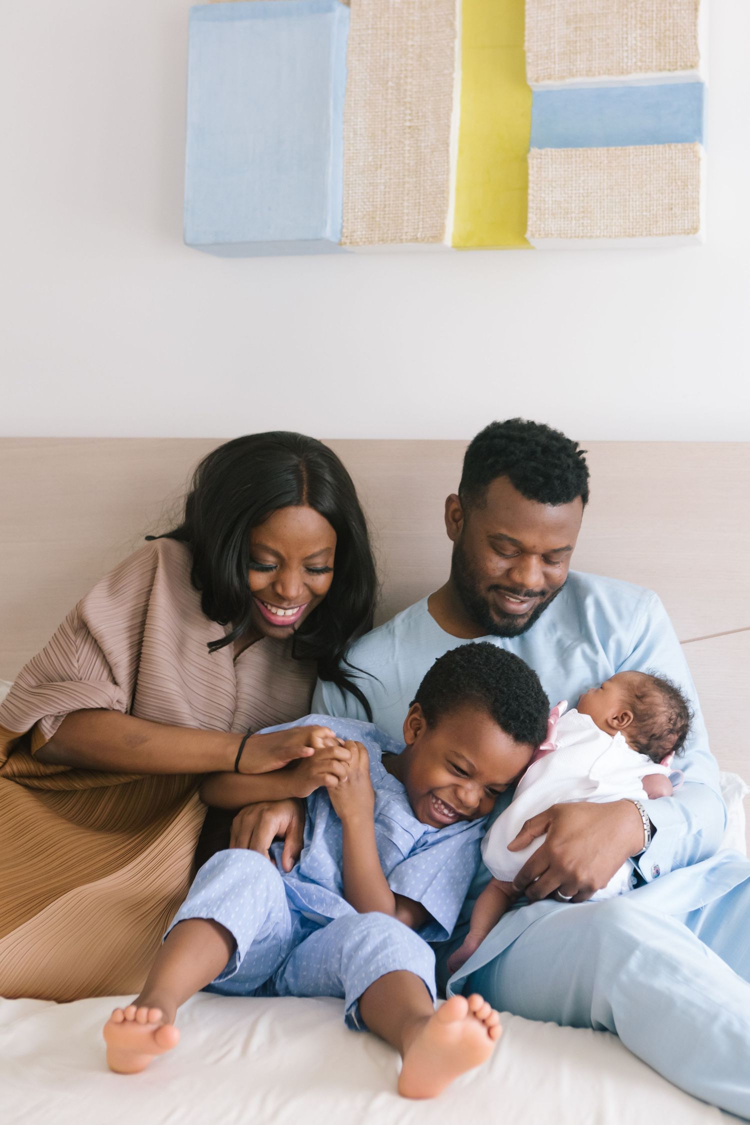 a black family in bed with their toddler son and newborn baby during a candid moment on a session by Paula Ortiz