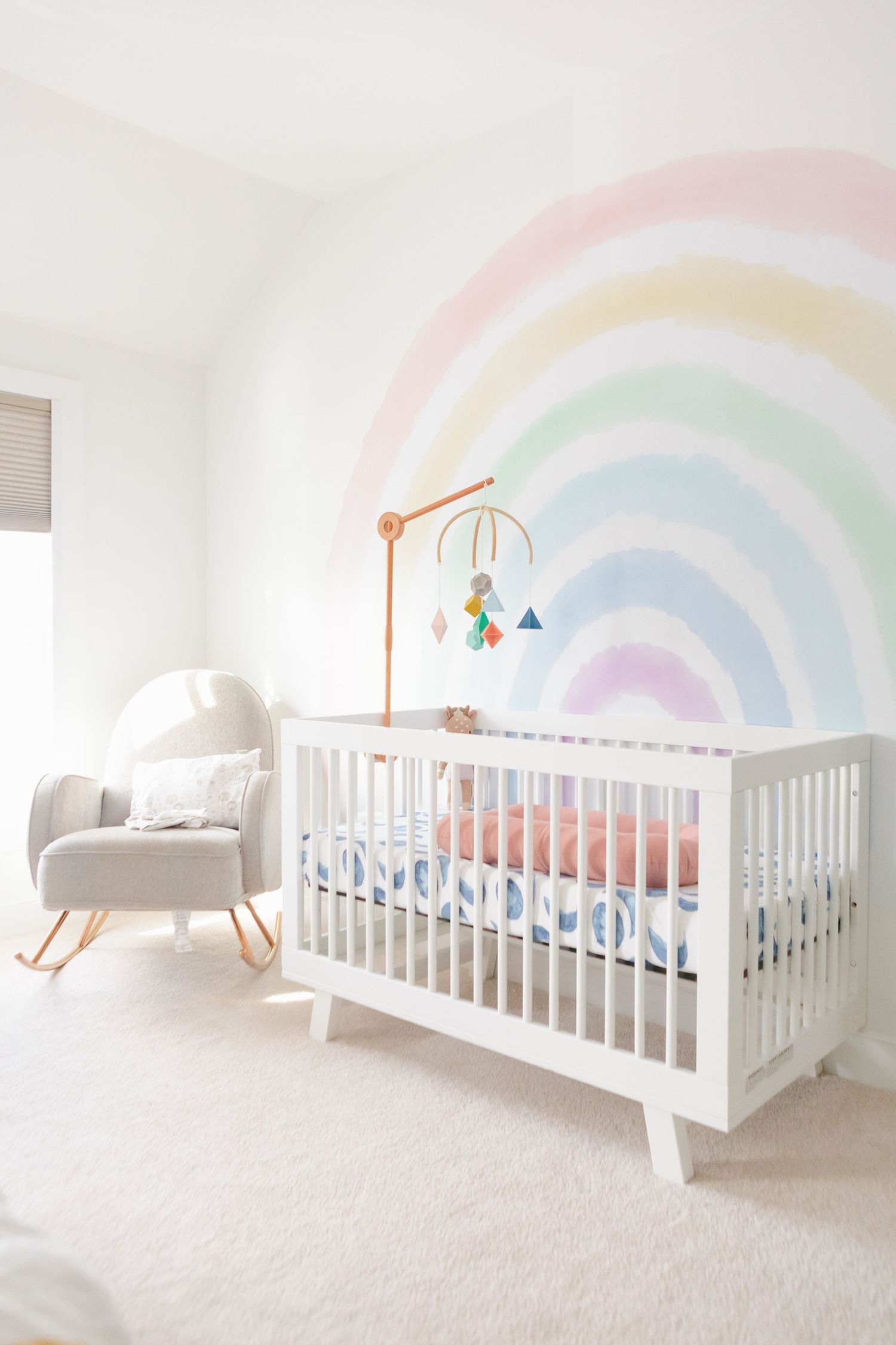a view of interior decor for a nursery with pastel rainbow wall decal and west elm white crib photographed by Paula O