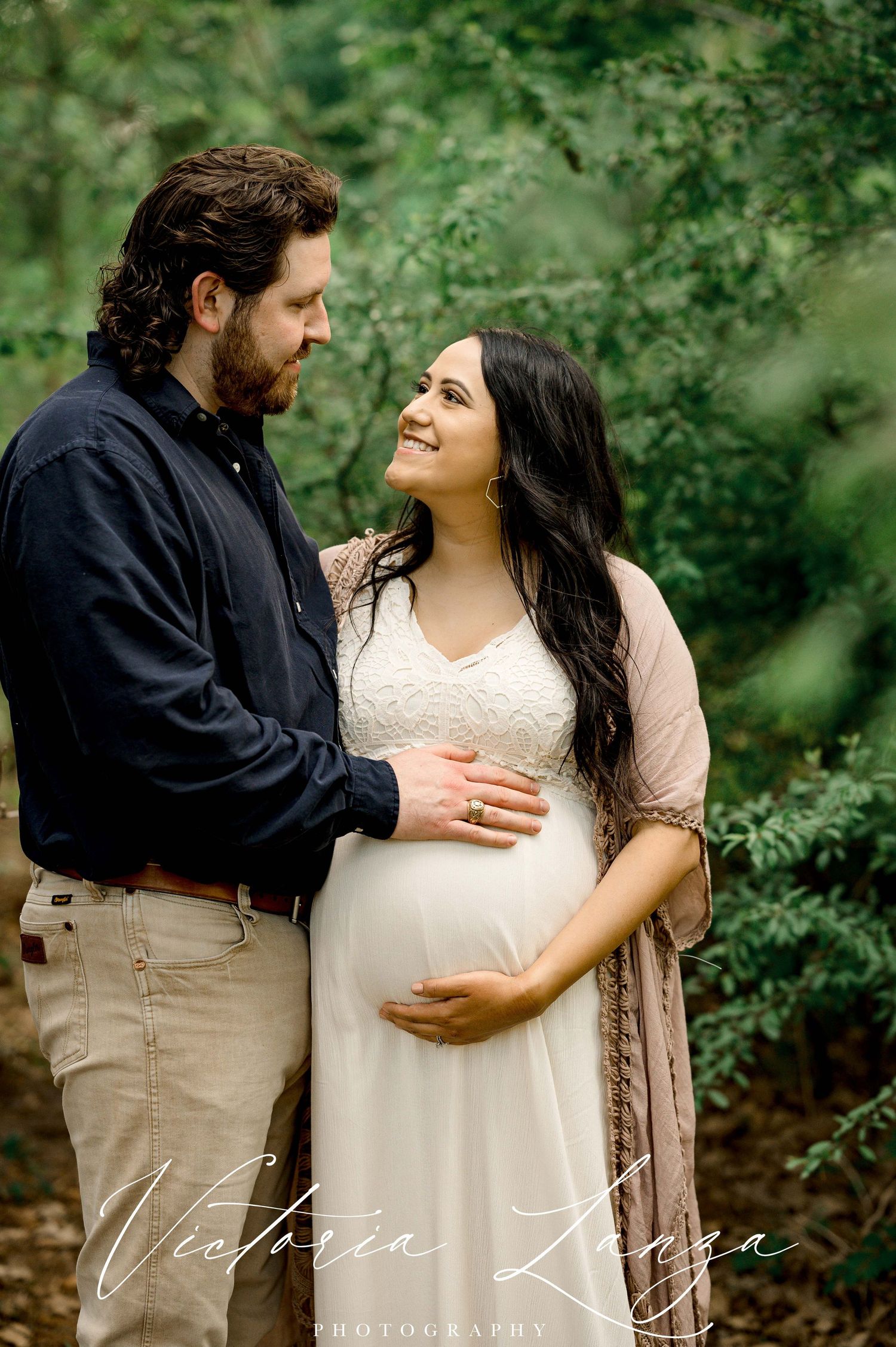Intimate maternity portrait in a lush forest setting.