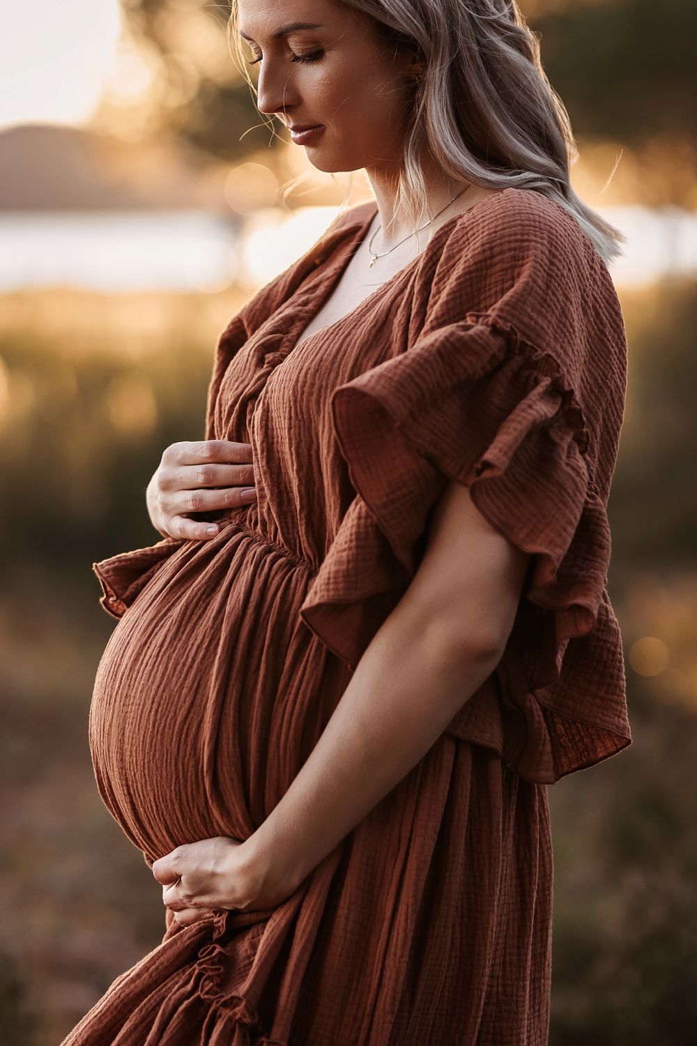 gravid kvinne i lang kjole, gravidfotografering i solnedgang