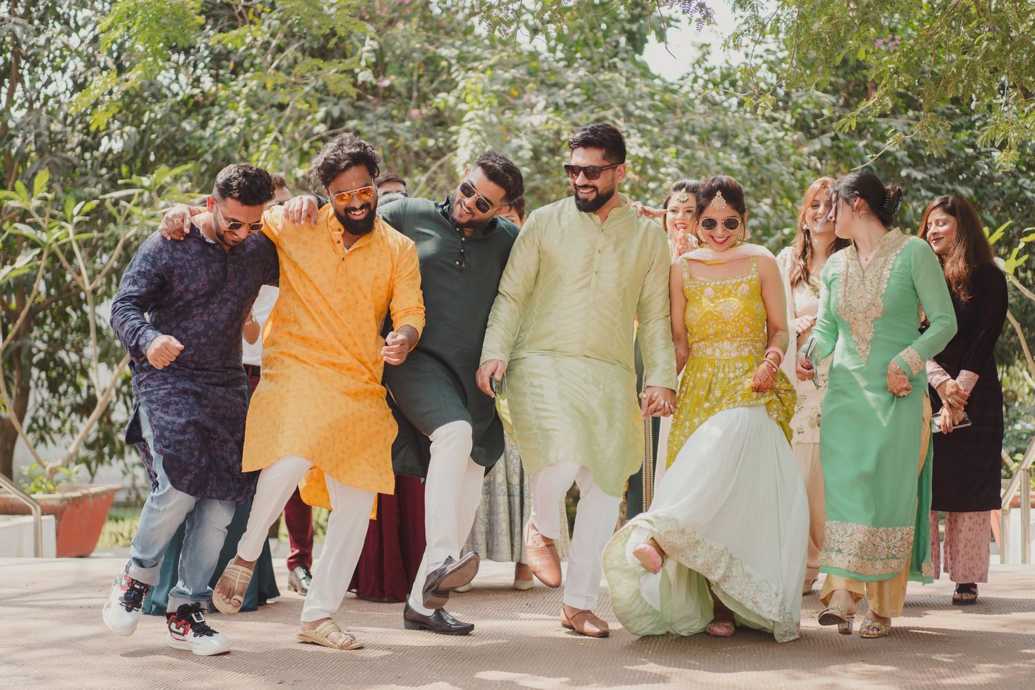 Guests gather outdoors for a festive celebration wearing traditional Indian attire in vibrant colors.