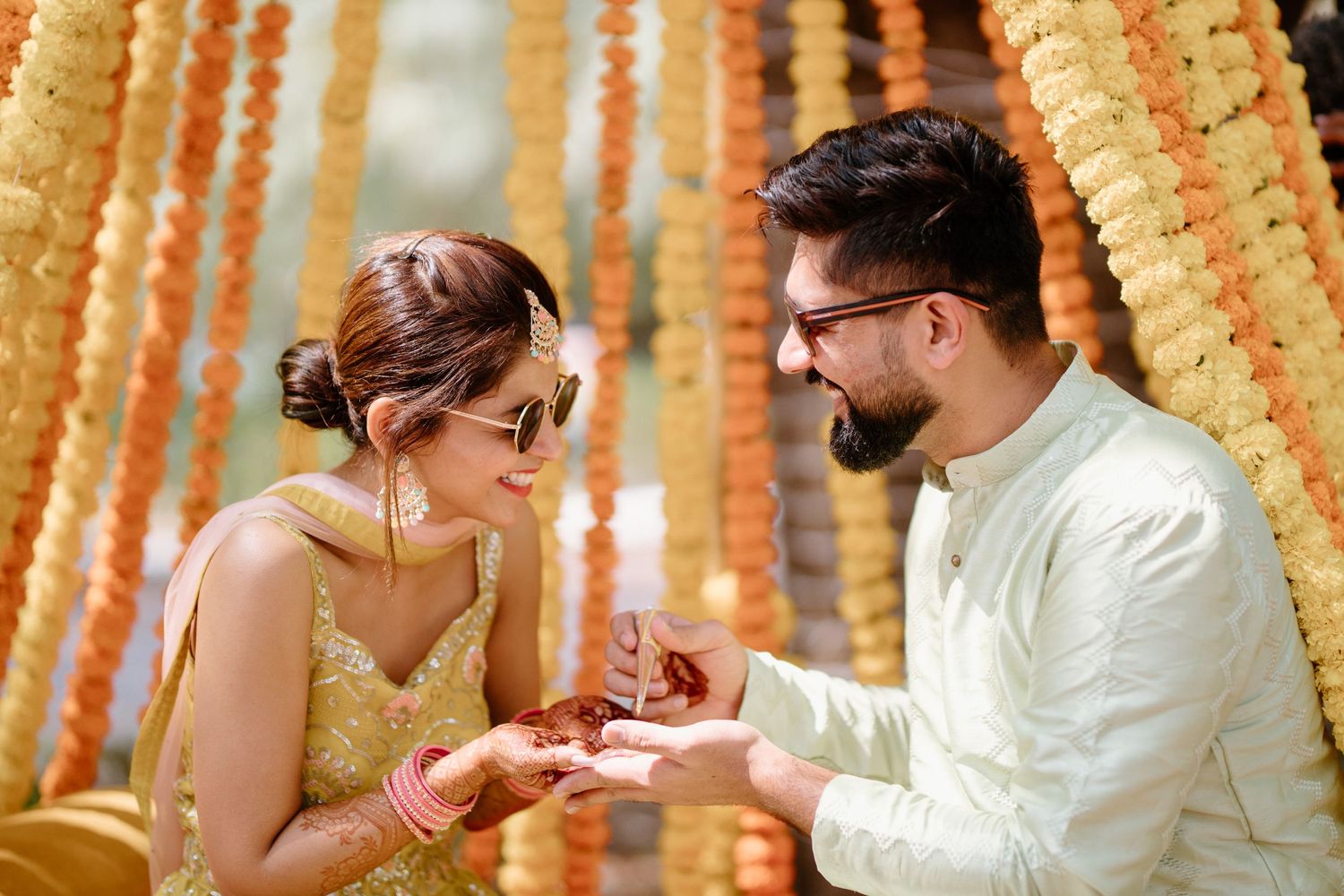 Traditional Indian ceremony moment under hanging marigold garlands and decorative elements.