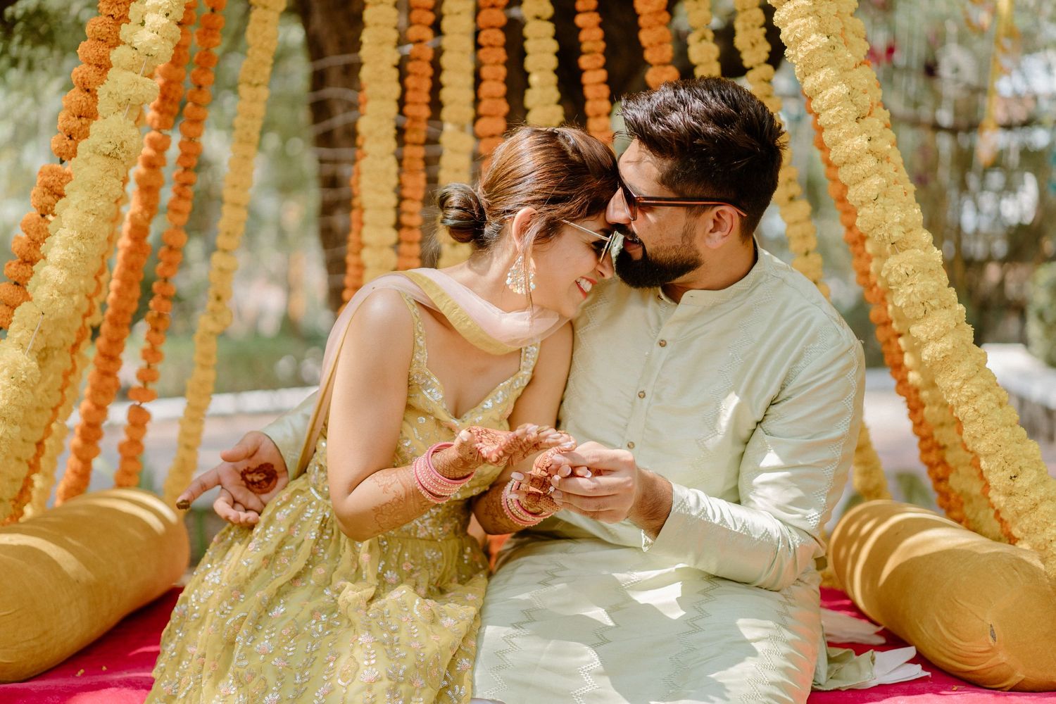Intimate moment captured during ceremony under orange marigold flower decorations.