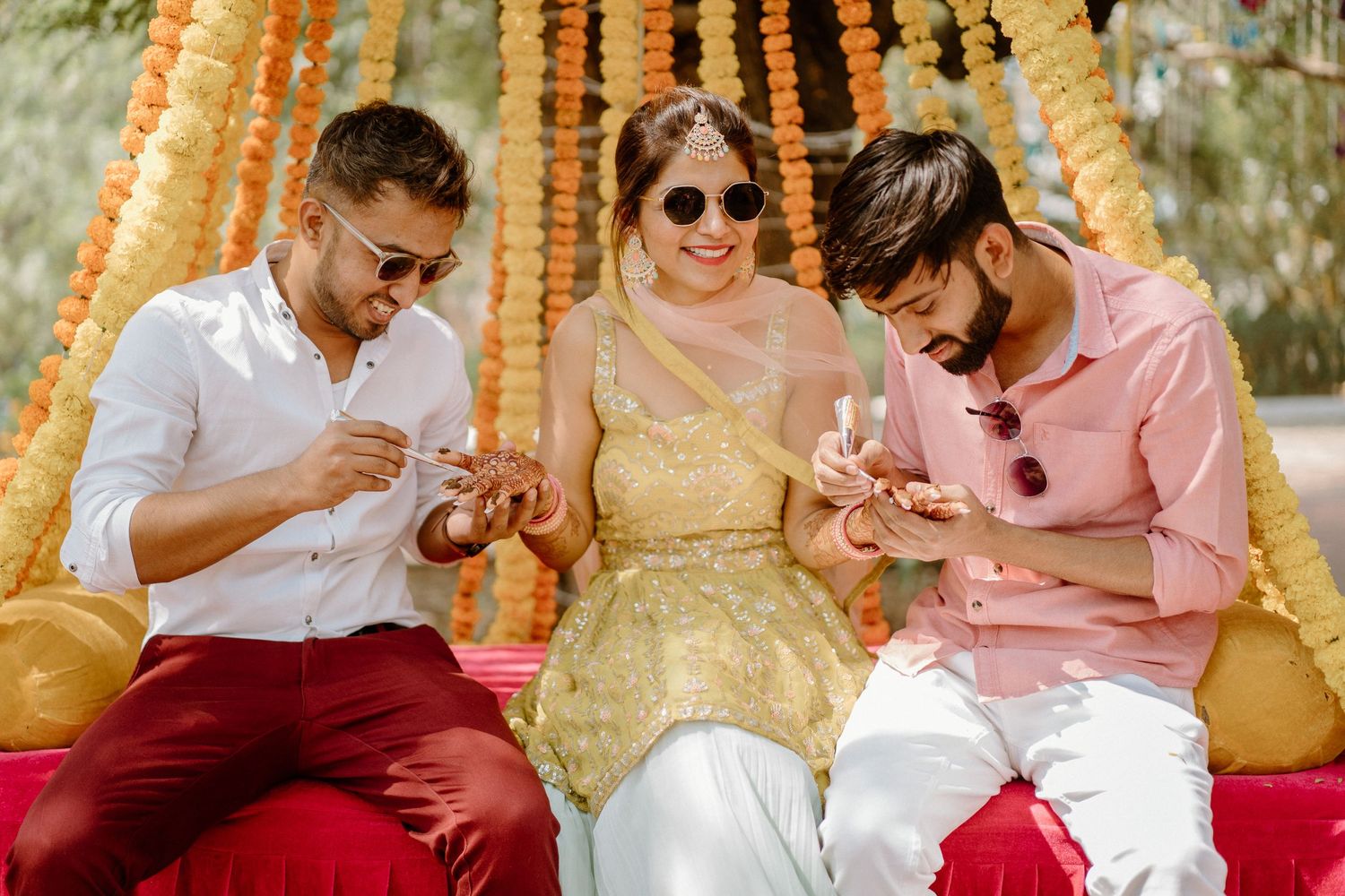 Guests enjoying candid moments under decorative marigold garlands at outdoor celebration.
