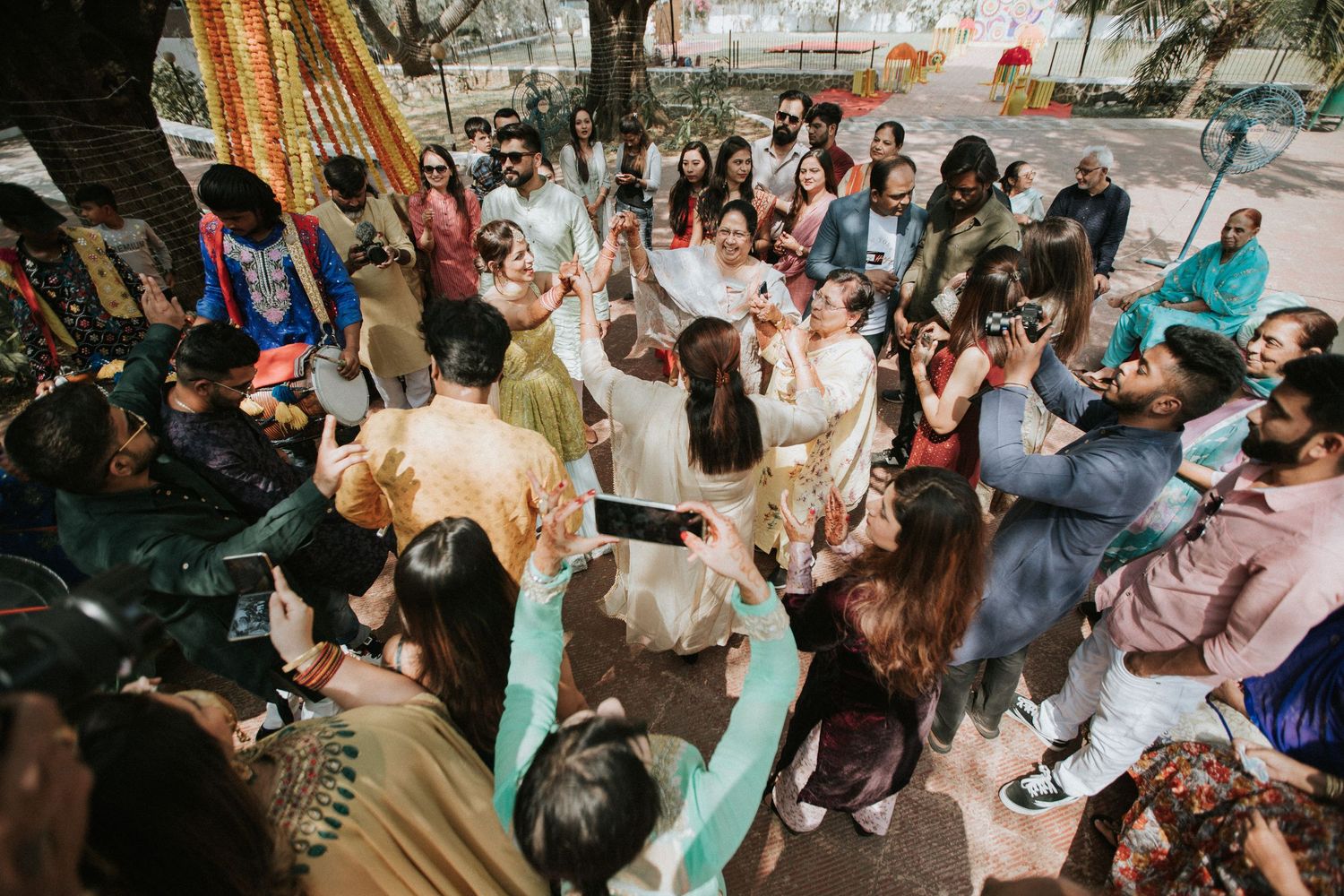 Large group celebrates outdoors with colorful attire and festive decorations.