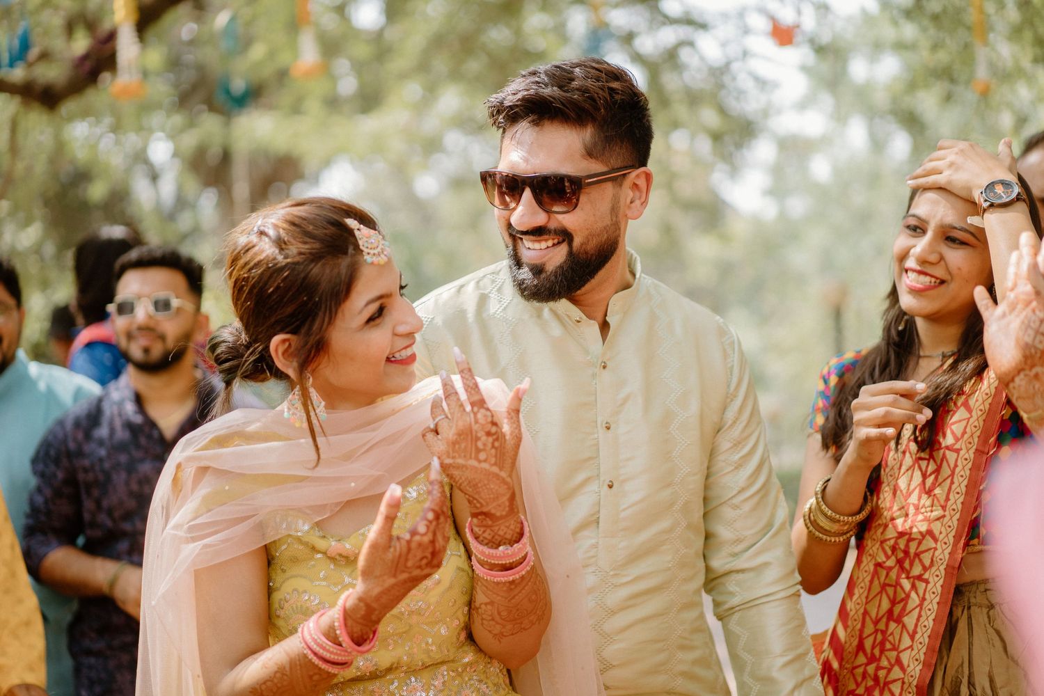 Joyful celebration at an outdoor Indian wedding ceremony with marigold decorations and natural surroundings.