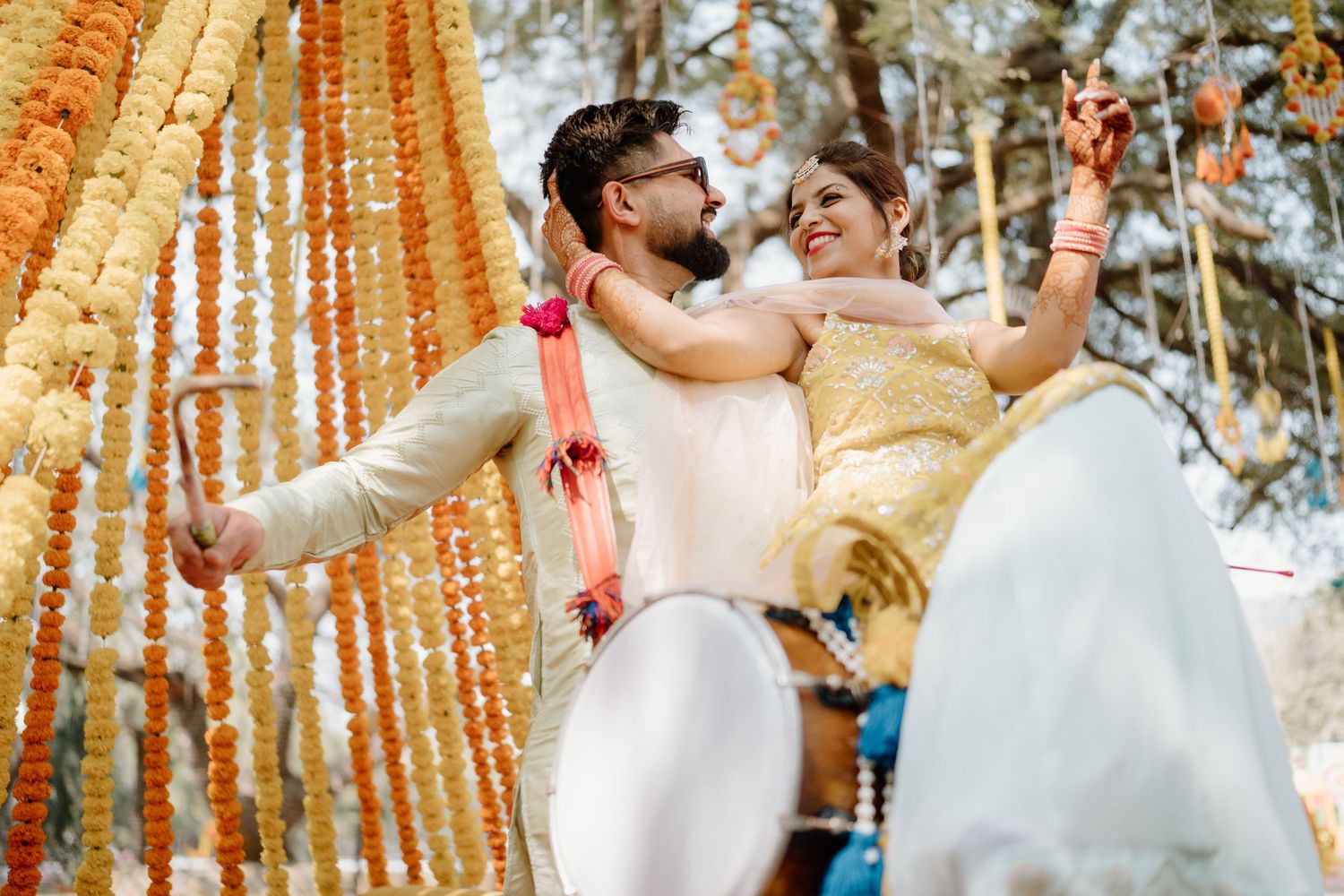 Traditional Indian wedding celebration with bright orange marigold decorations hanging outdoors.
