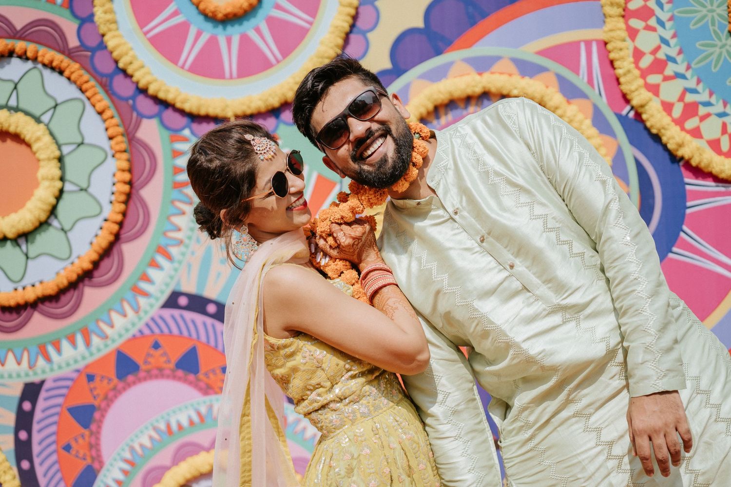 Candid celebration moments against a backdrop of colorful circular mandala patterns.