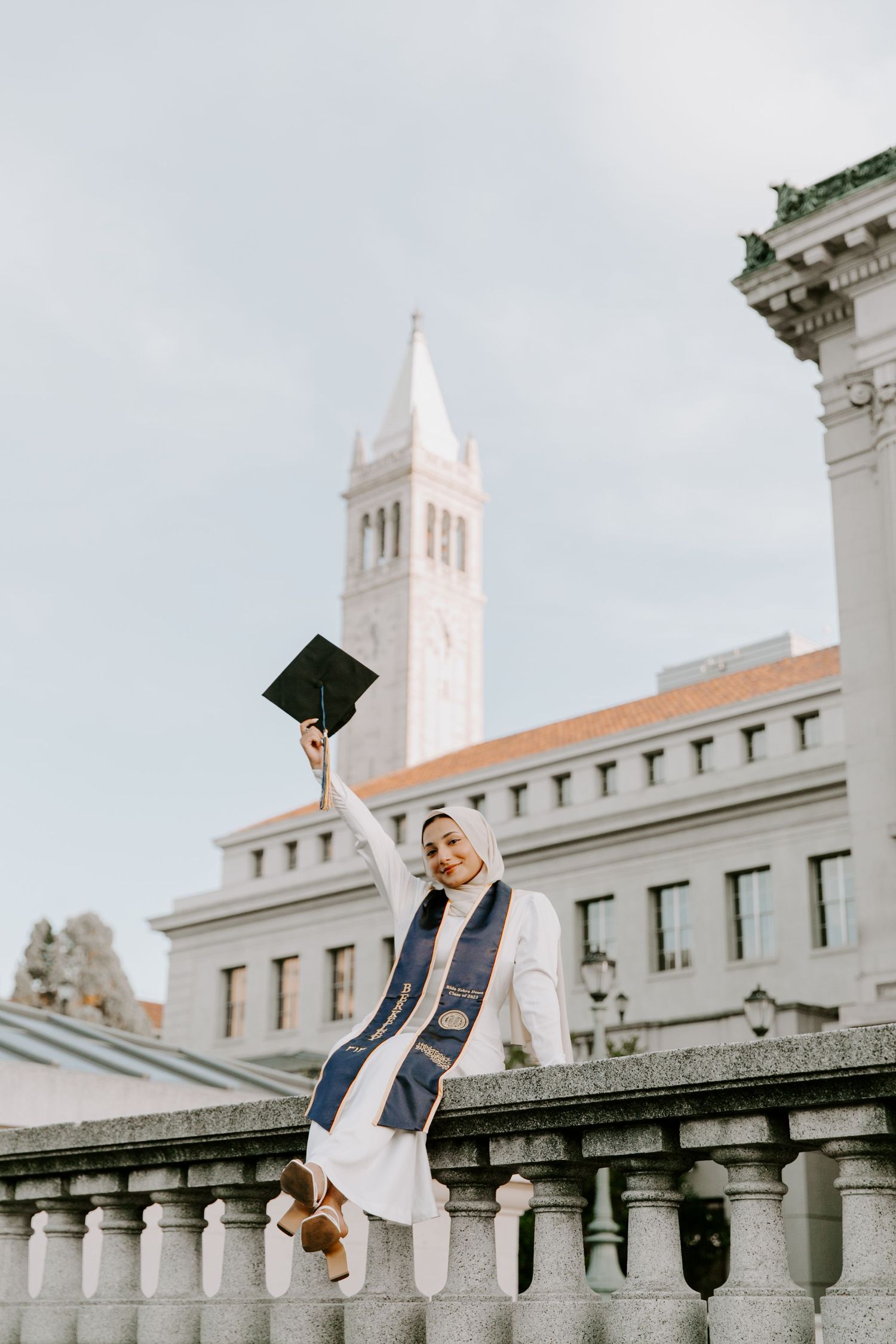Academic building with white stone balustrade and clocktower during graduation celebrations.