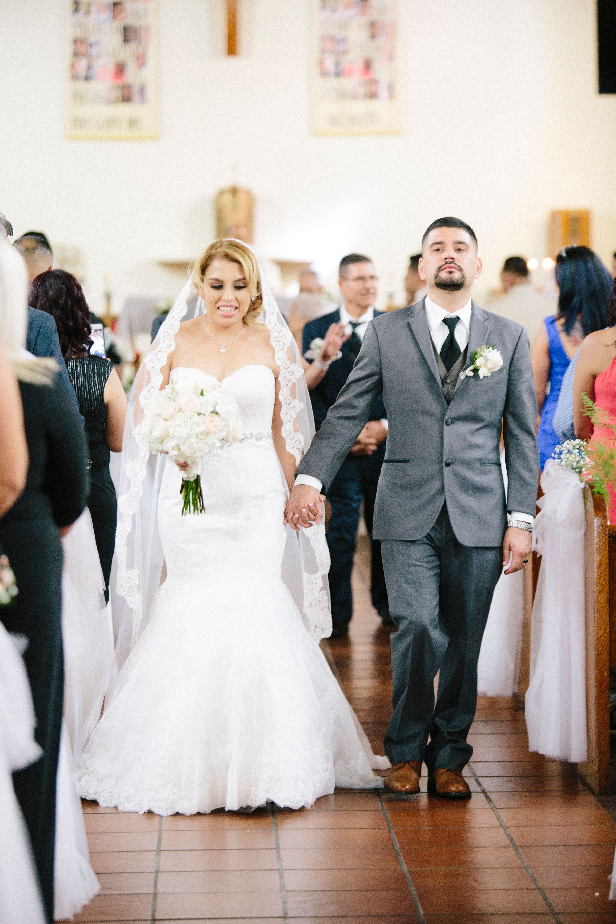 Wedding party celebrates in an indoor venue with white decor and hardwood floors.