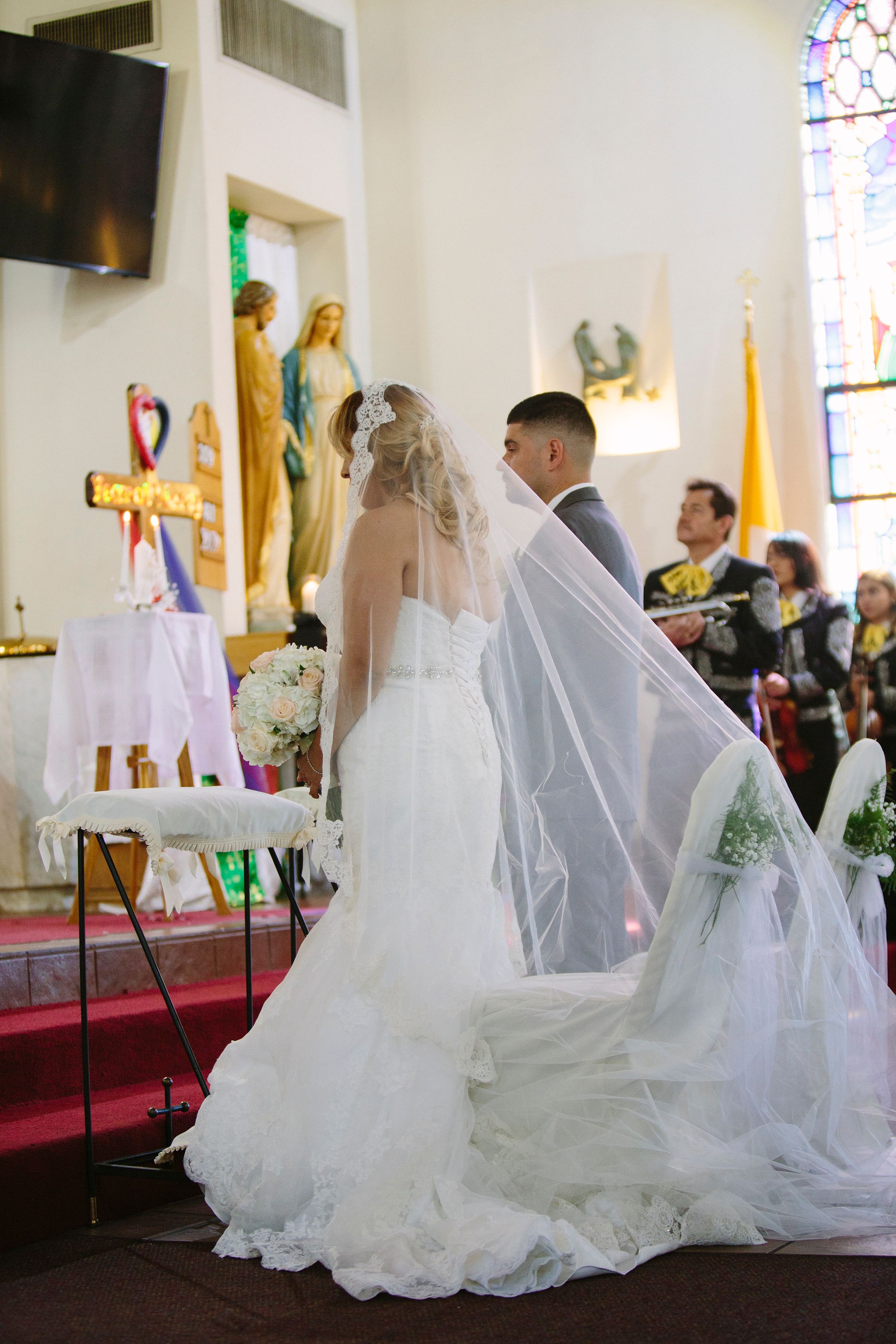Wedding ceremony in church with stained glass windows and flowing white dresses.