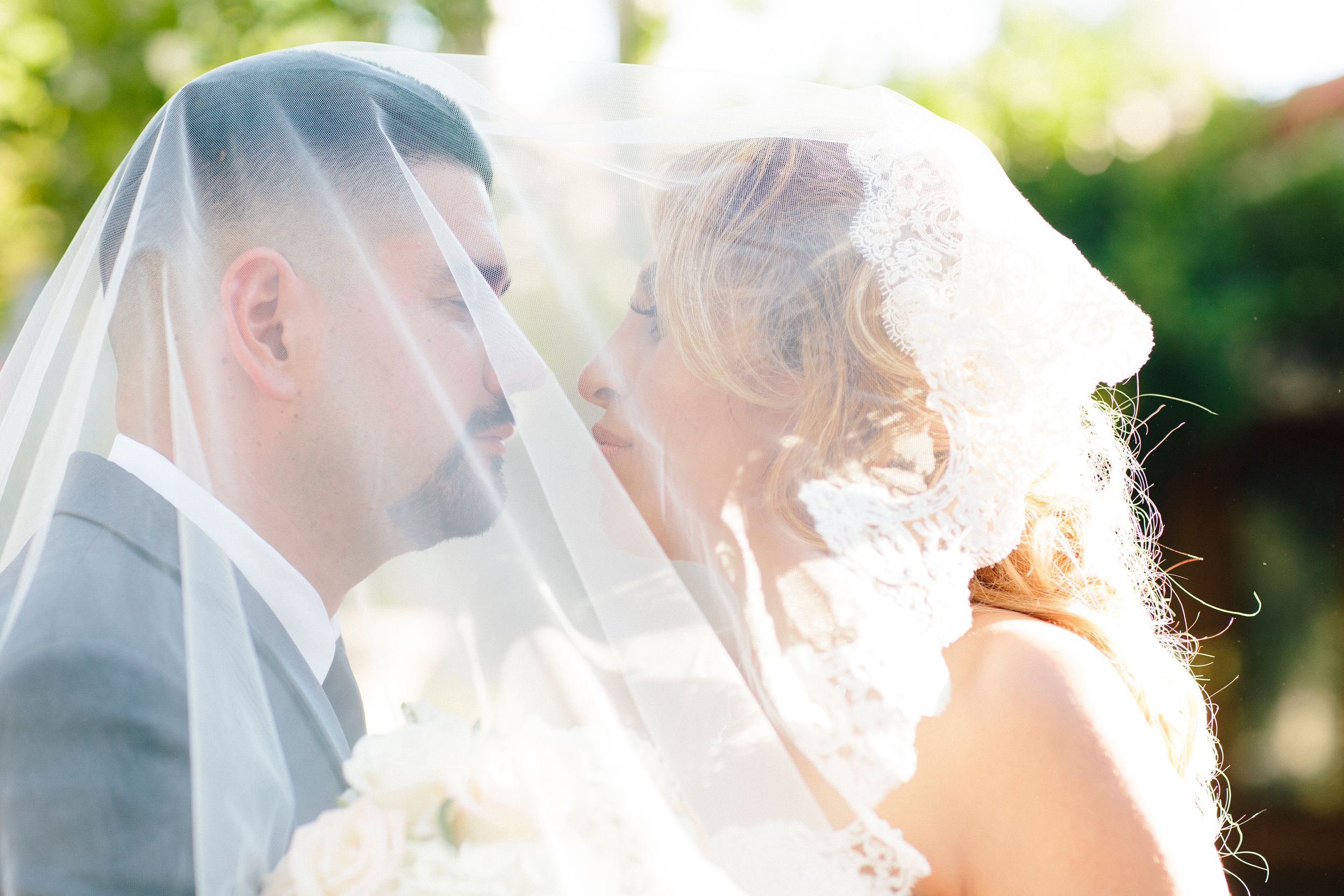 Soft focus wedding portraits showing intimate moments through a delicate veil.