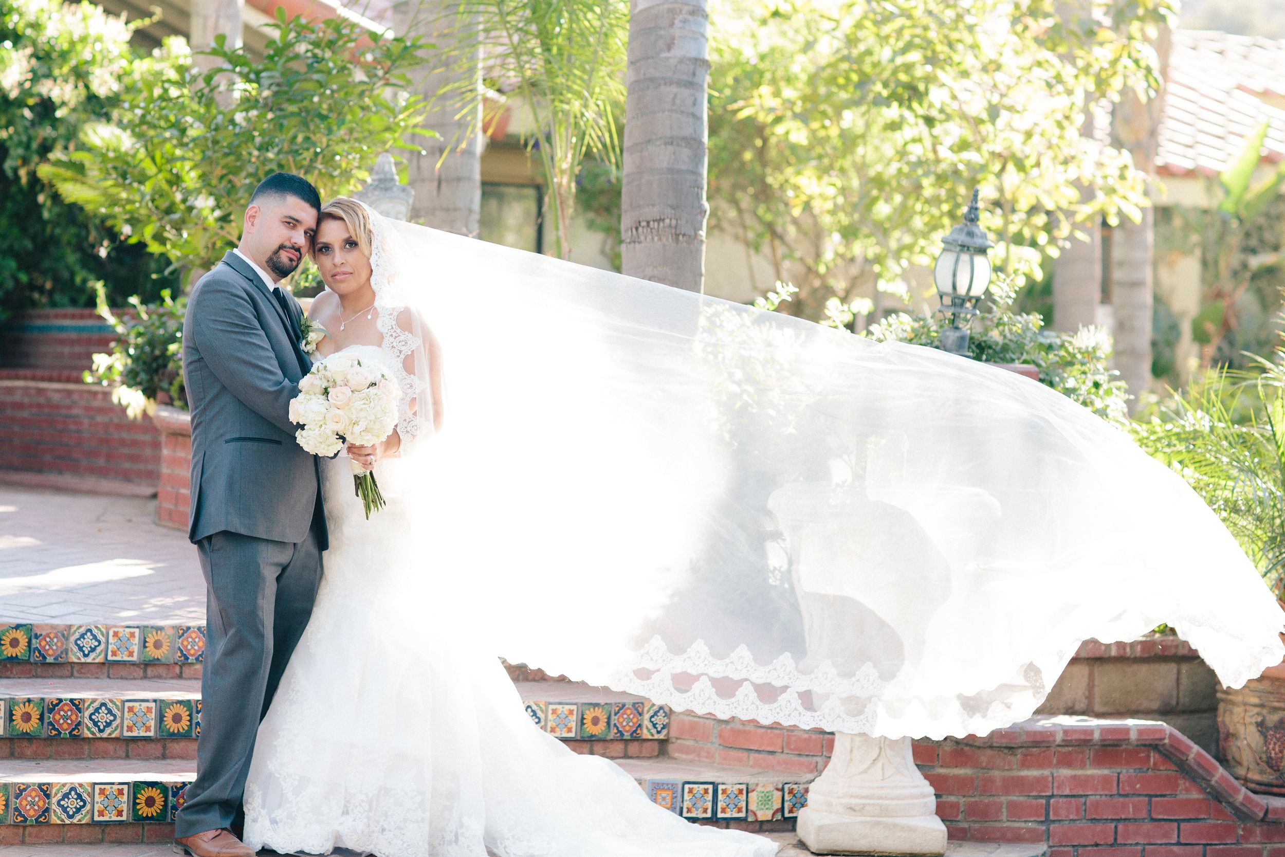 Romantic wedding couple poses along a Spanish-style building with decorative tiles.