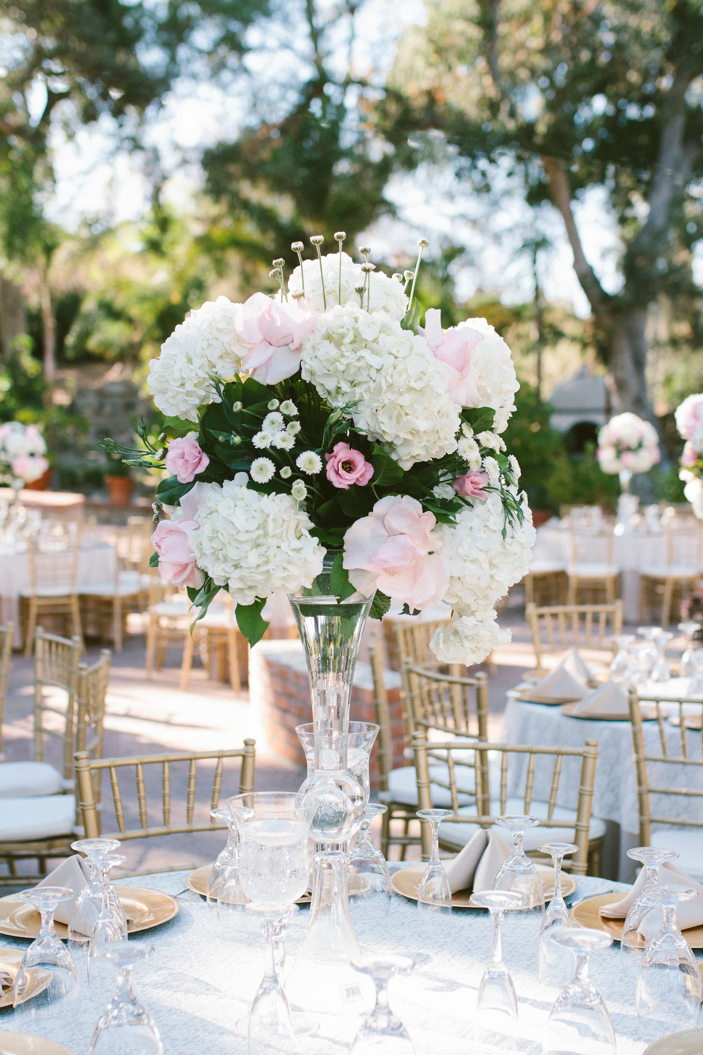 Elegant wedding reception table with white hydrangea and pink rose centerpieces.