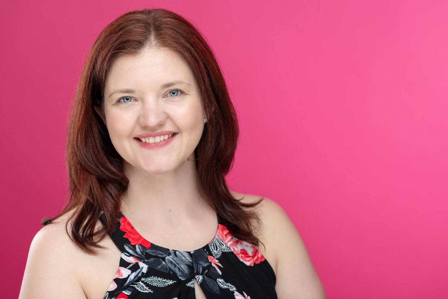 Professional headshot against bright pink background.