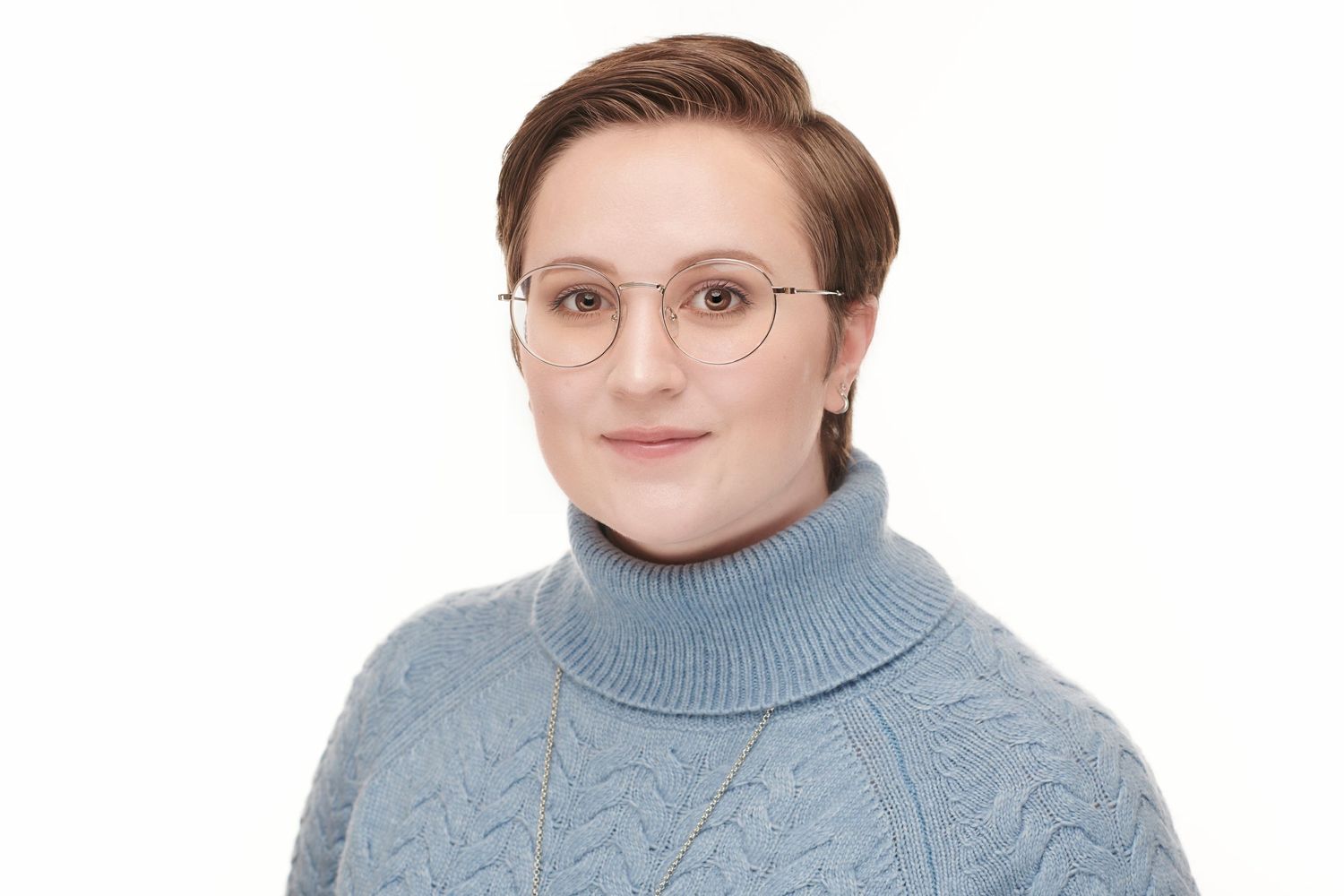 Professional headshot of someone wearing a grey turtleneck sweater and round glasses.