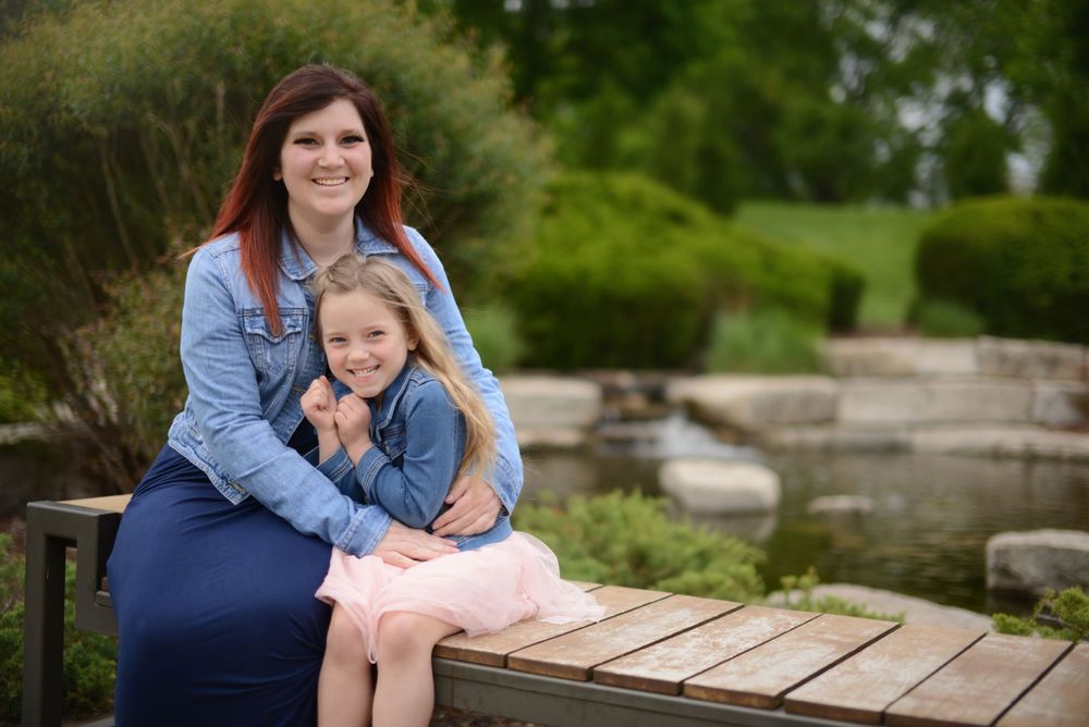 mother with arms around daughter while sitting on a bench