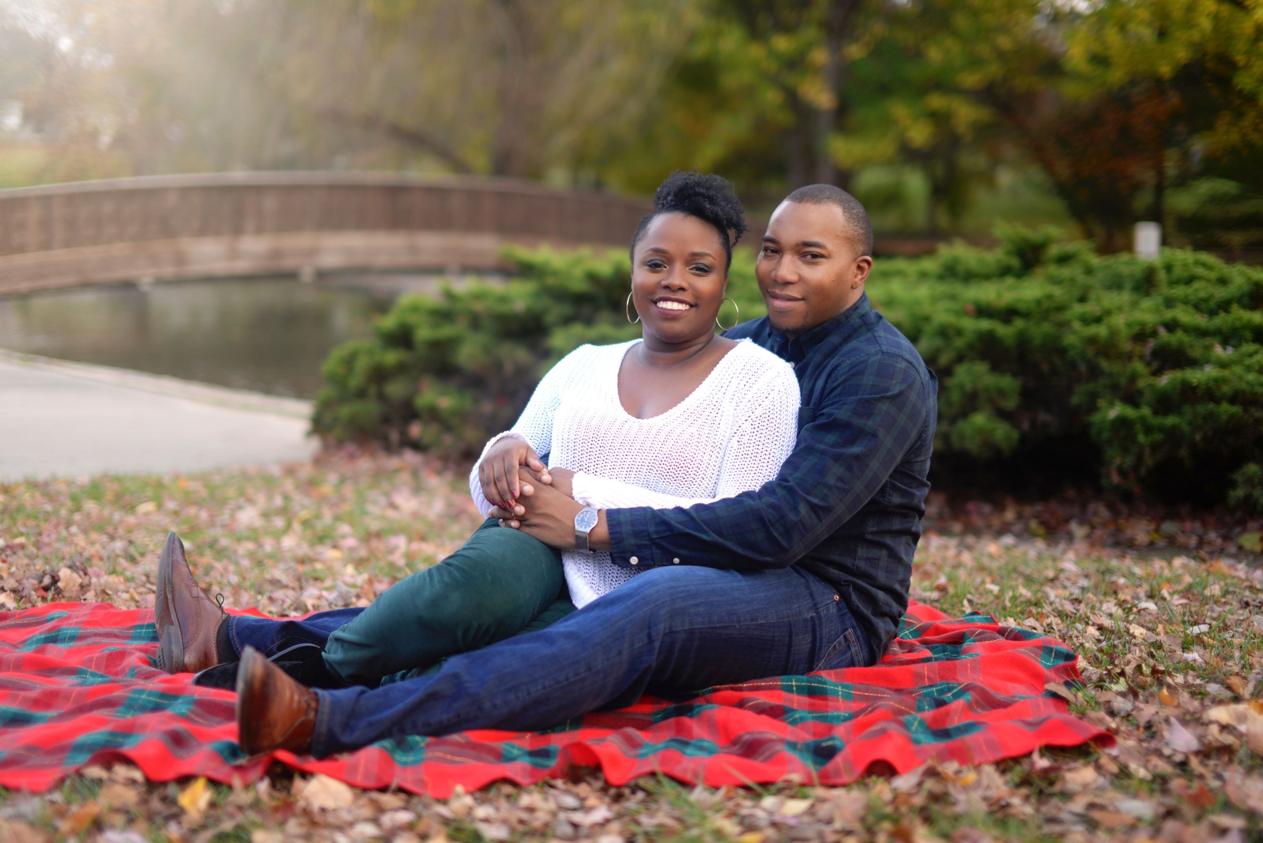 man holding woman in front of him while sitting on blanket together