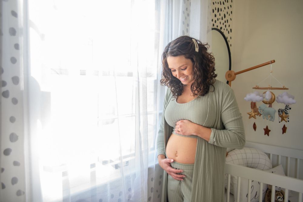 woman in nursery holding pregnant belly
