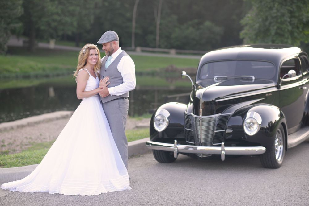 husband looking at bride in front of vintage car