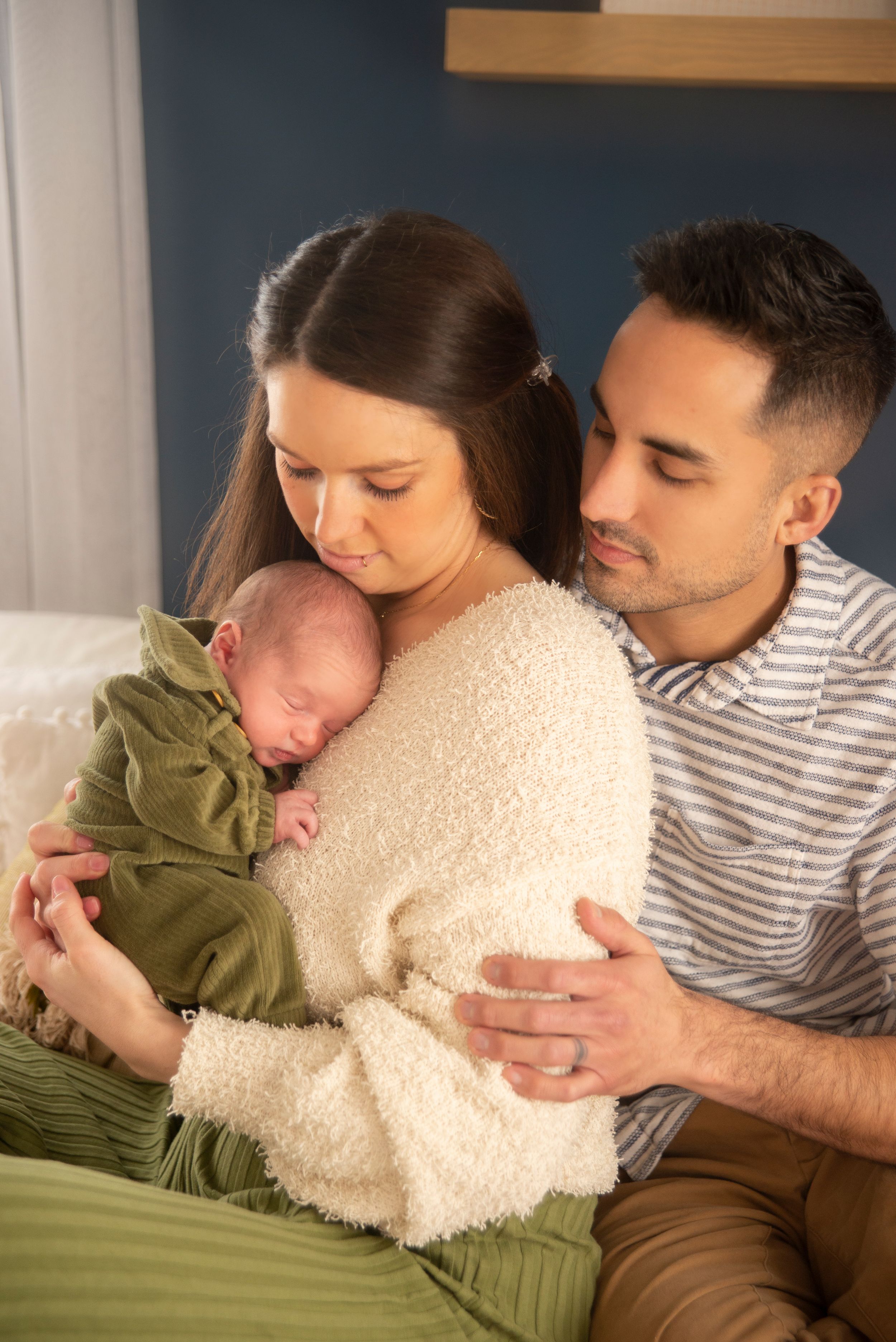 mother holding newborn baby with father behind her